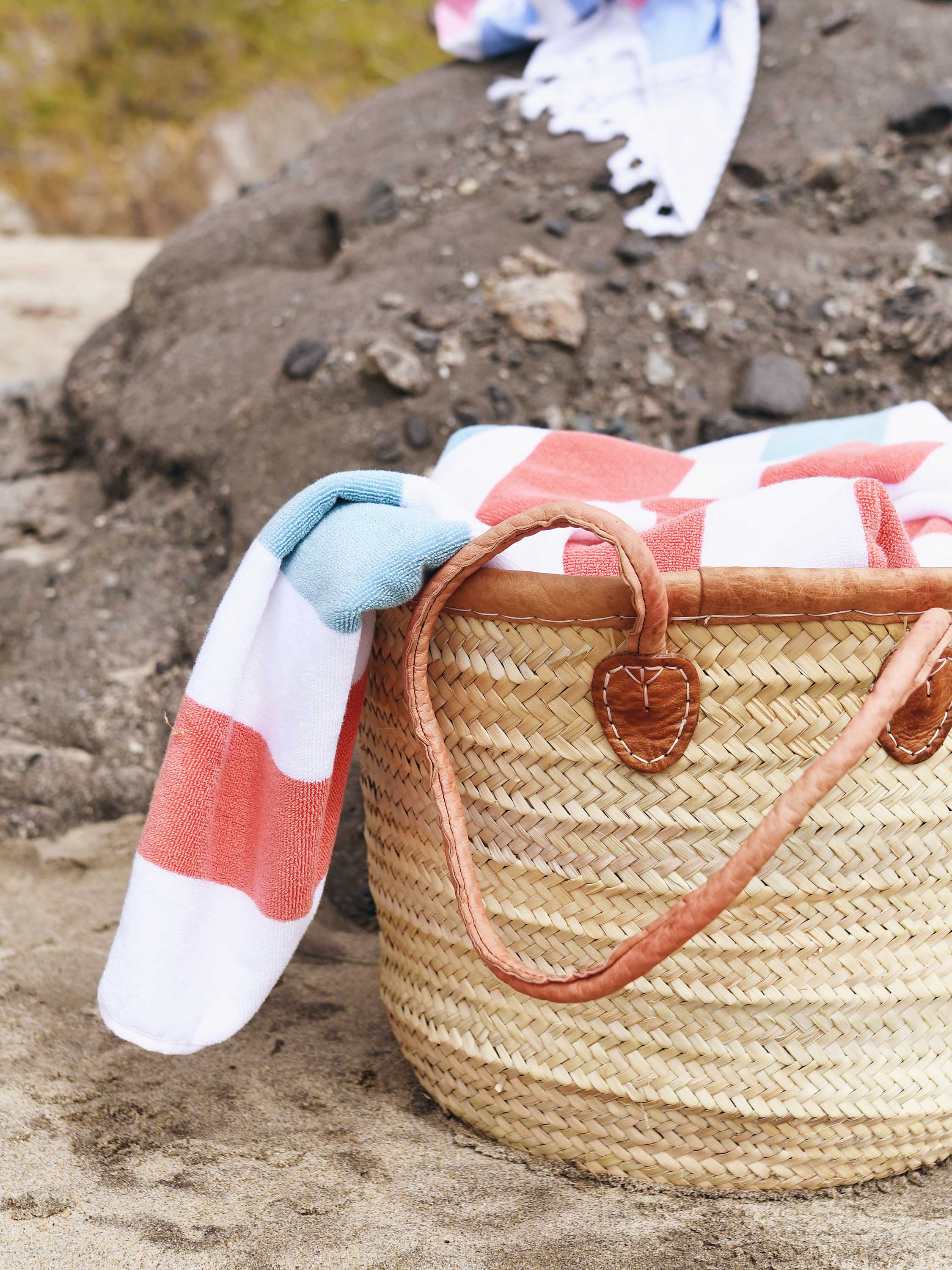 Woven basket with a striped towel on a rocky surface