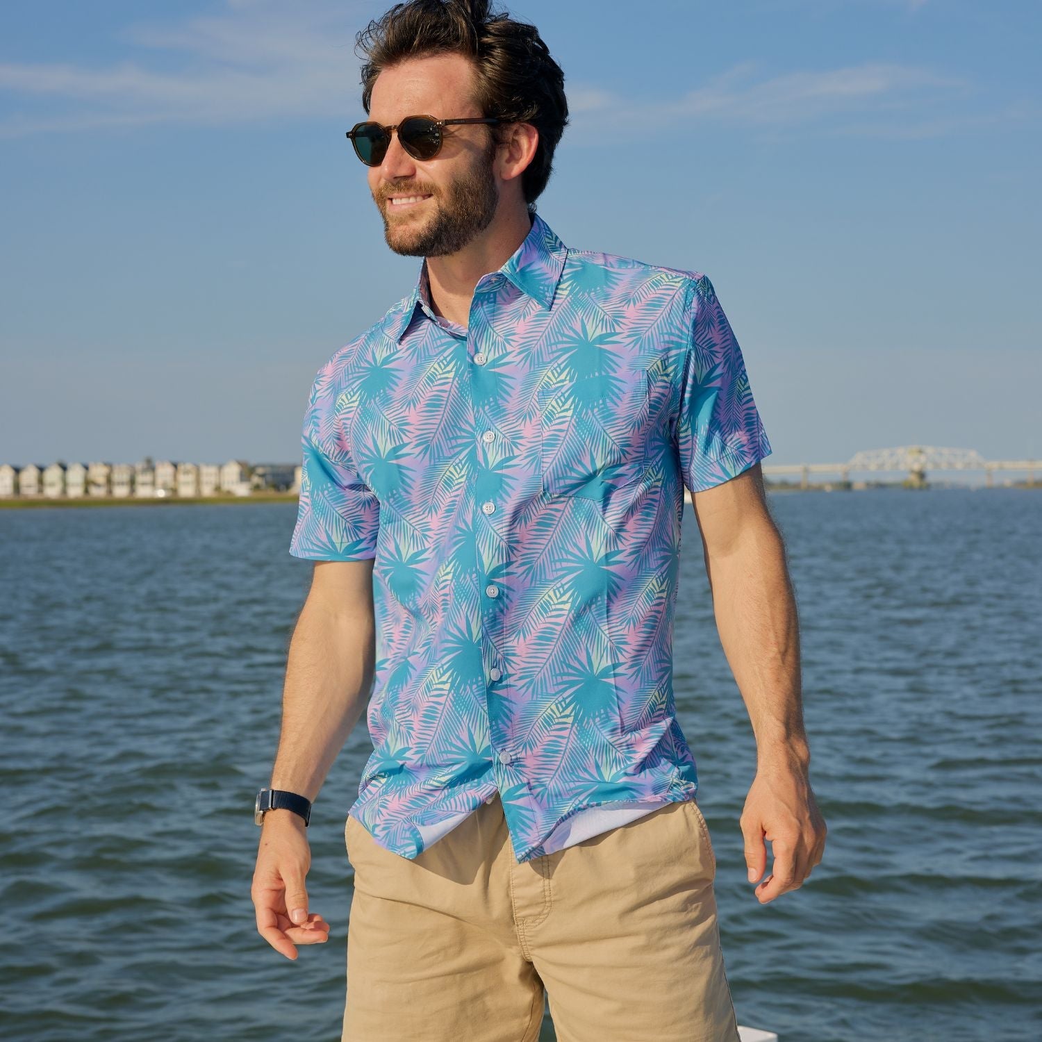 Man wearing a colorful patterned shirt standing by a body of water.