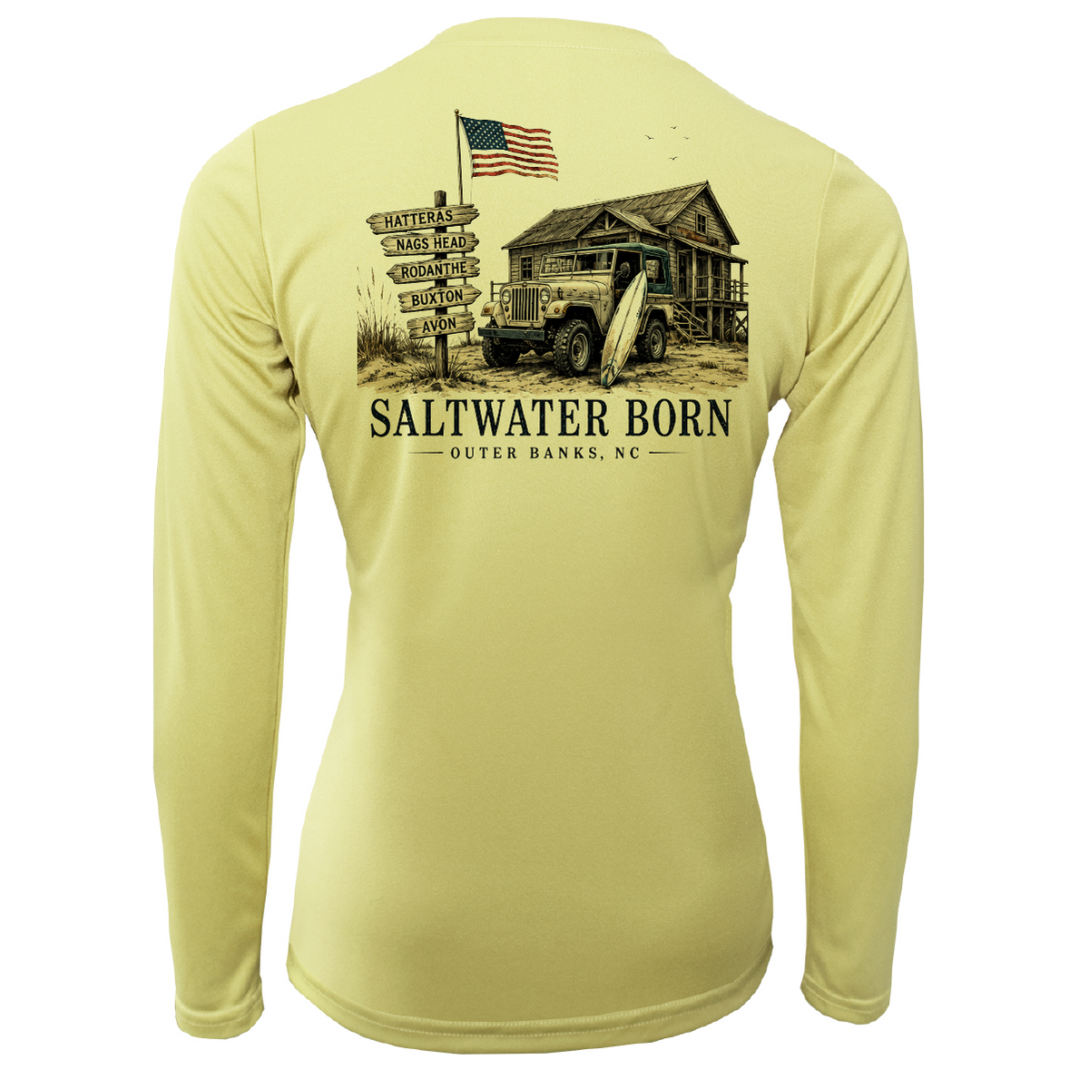 A pale yellow long-sleeve performance shirt shown from the back, featuring a large vintage-style graphic of a rustic cabin, an American flag, a signpost, and the text 'SALTWATER BORN OUTER BANKS, NC'.