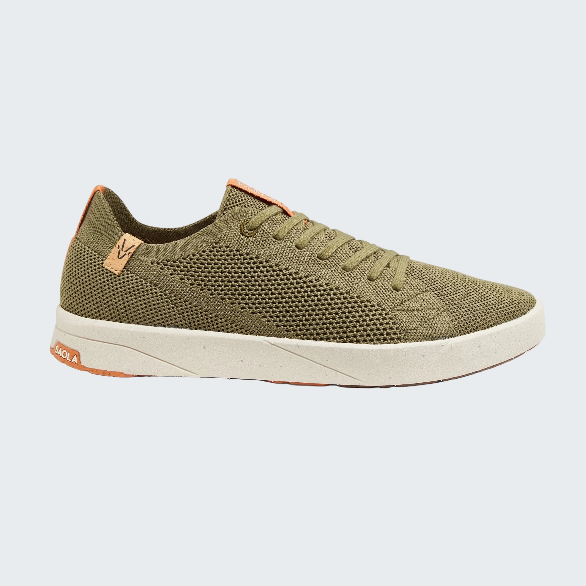 A single low-top sneaker shown in profile against a light gray background. The shoe features an olive green mesh upper, matching green laces, a cream-colored midsole, and small orange accents on the heel and tongue.