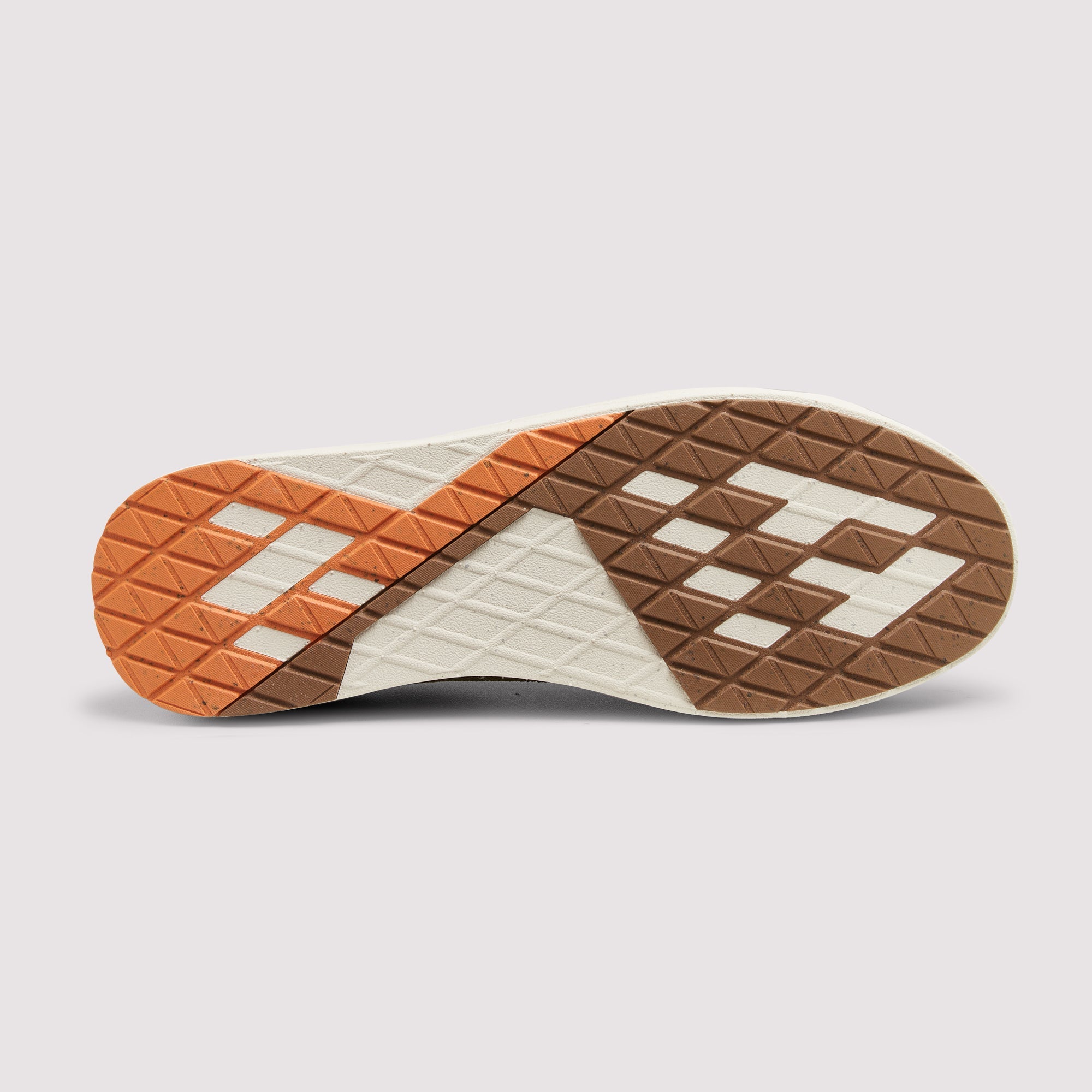 The outsole of a sneaker shown from a top-down view, featuring a geometric pattern of orange, brown, and off-white textured rubber blocks on a light gray background.