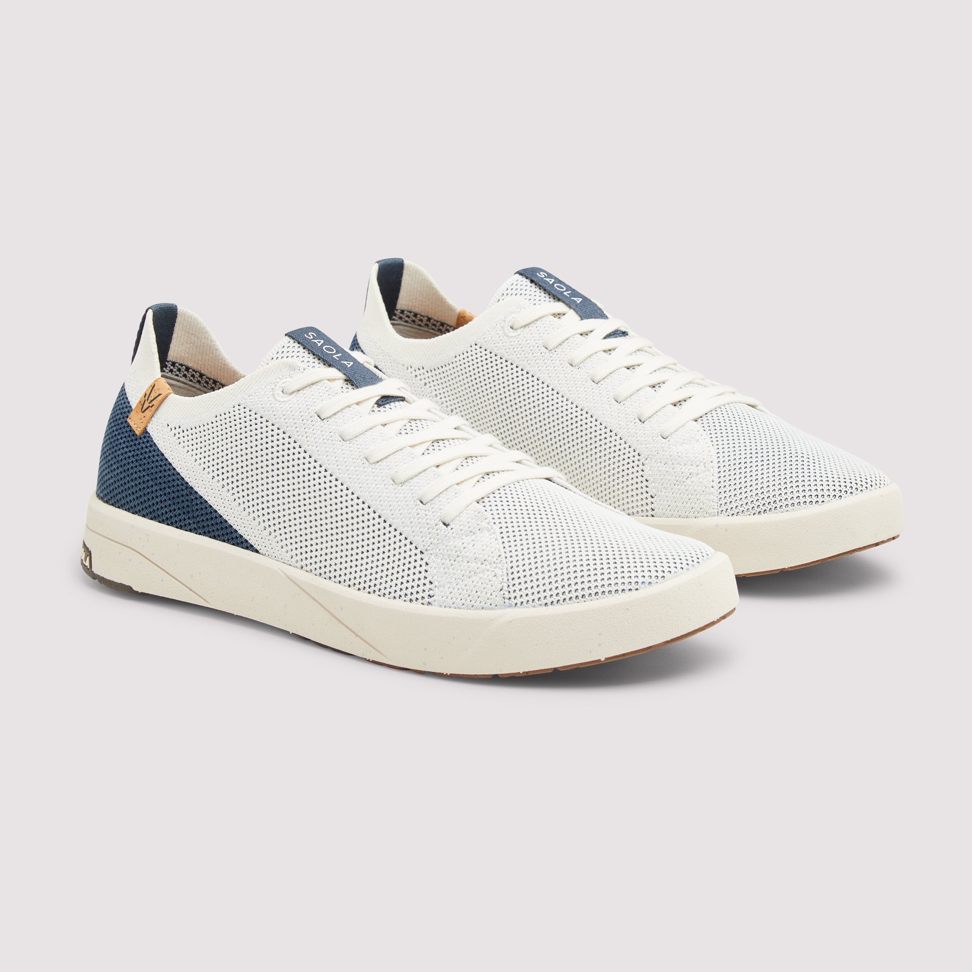 A pair of white mesh sneakers with navy blue heel panels and white laces, shown on a light gray background.
