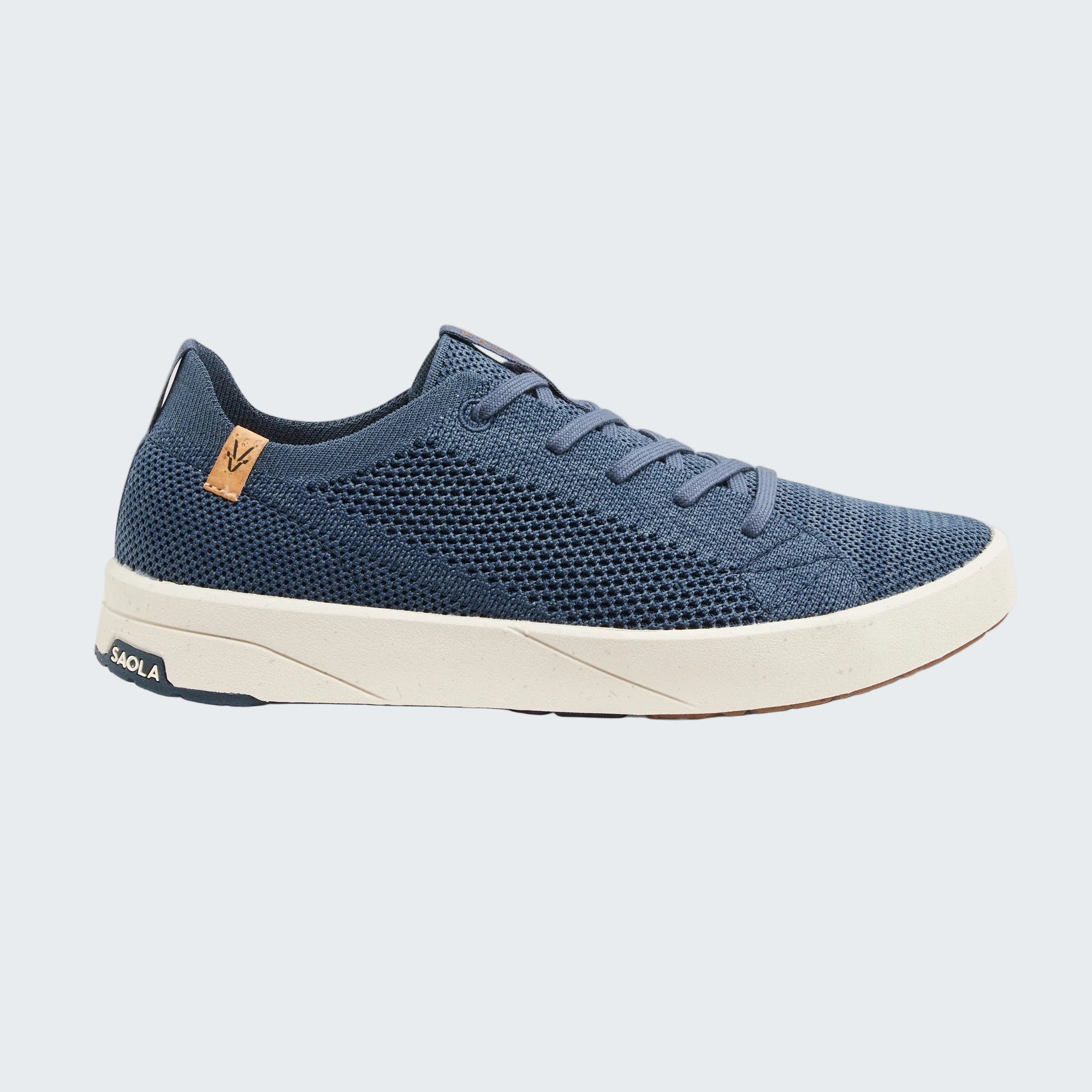 A single low-top sneaker in navy blue knit fabric with a thick off-white sole, shown in a side profile on a light gray background. The brand name 'SOLA' is visible on the heel of the sole and on a small tan leather tag near the collar.