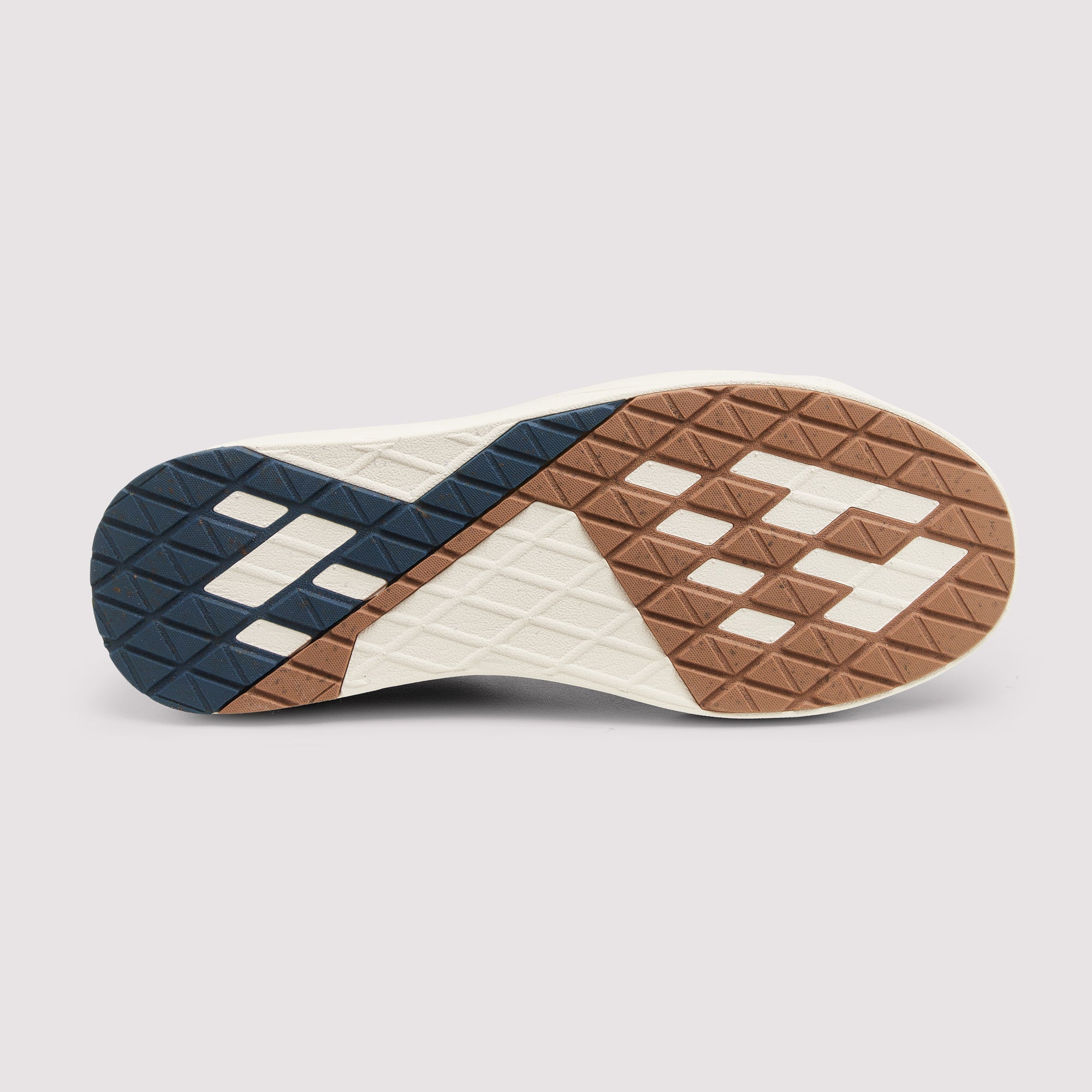 The outsole of a sneaker shown from a top-down view, featuring a geometric pattern in navy blue, brown, and off-white rubber with a diamond tread design.