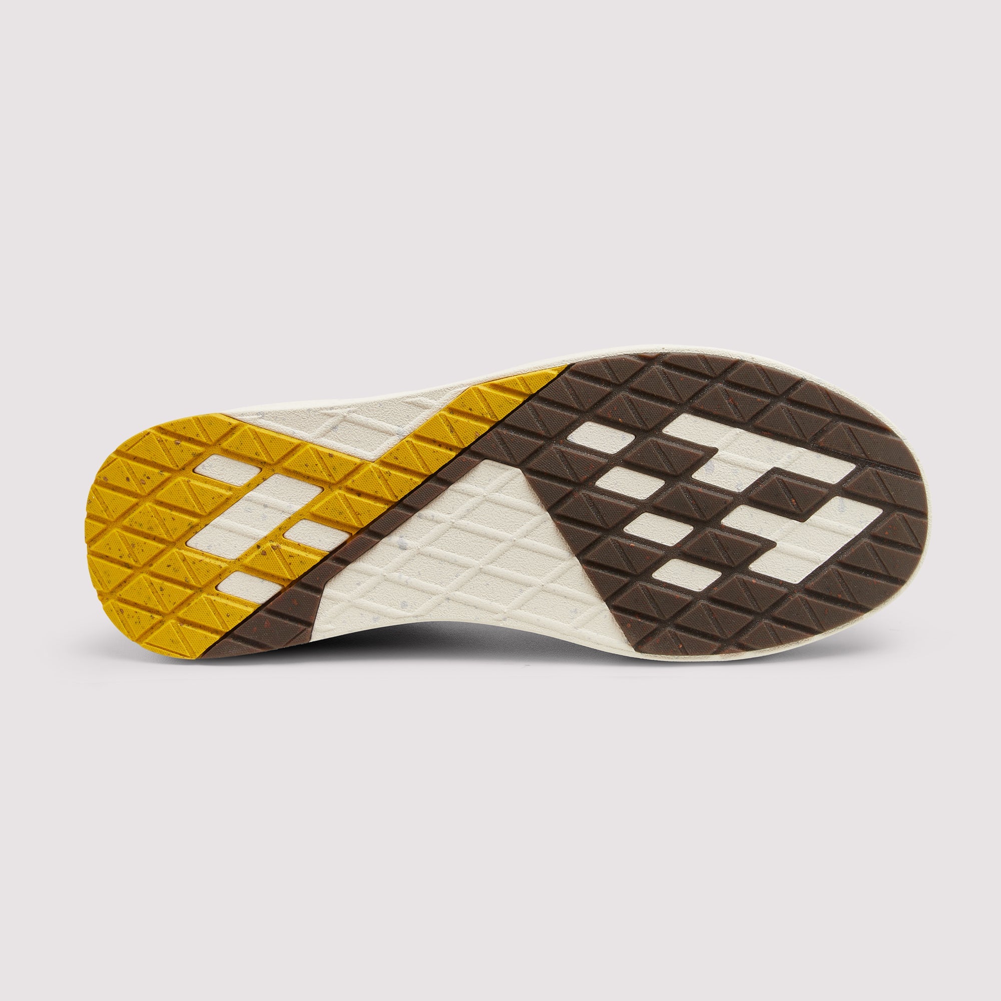 The outsole of a sneaker shown from a top-down view, featuring a geometric pattern of yellow, dark brown, and off-white rubber with textured tread blocks.