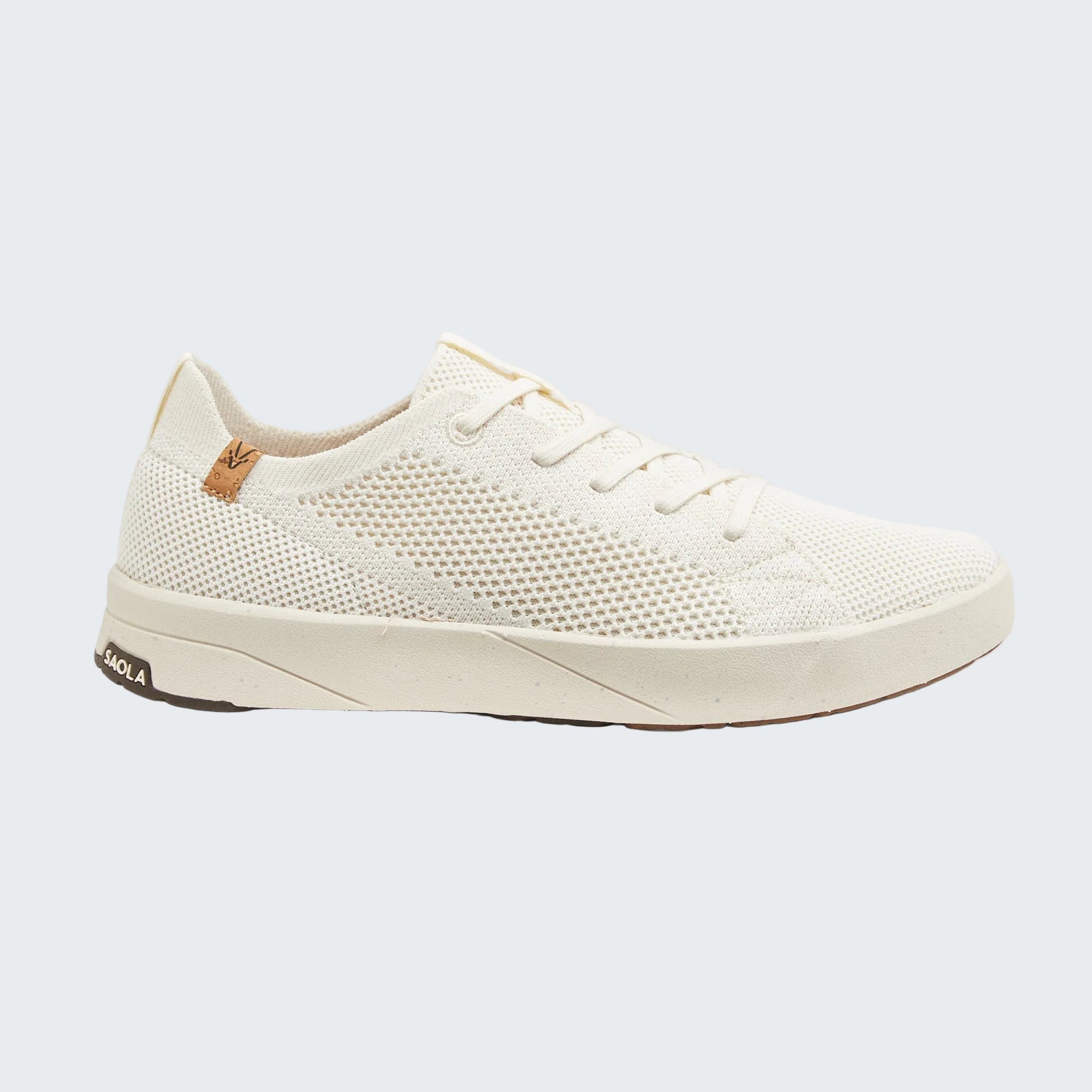 A low-top sneaker by Agla in off-white mesh and textile materials, featuring a thick off-white sole, white laces, and a small tan leather heel tab on a light gray background.
