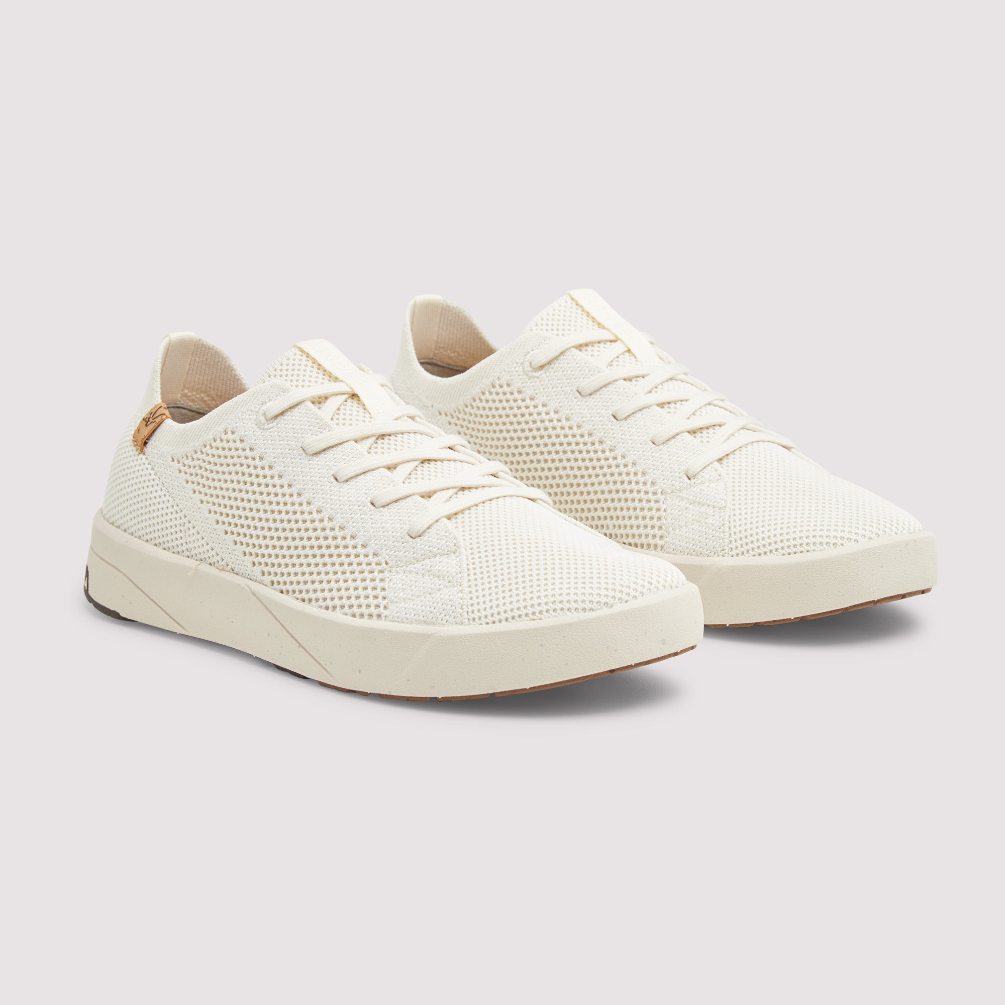 A pair of low-top knit sneakers in off-white/cream, featuring a textured knit upper, matching laces, and thick platform-style soles, shown against a solid light gray background.