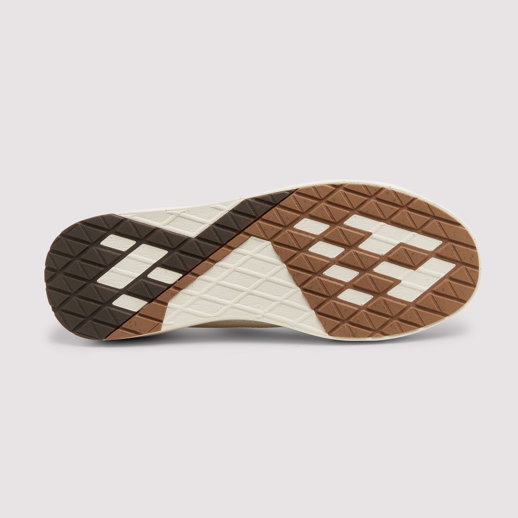 The outsole of a sneaker shown from a top-down view, featuring a geometric pattern in brown, dark brown, and off-white with a diamond tread design.