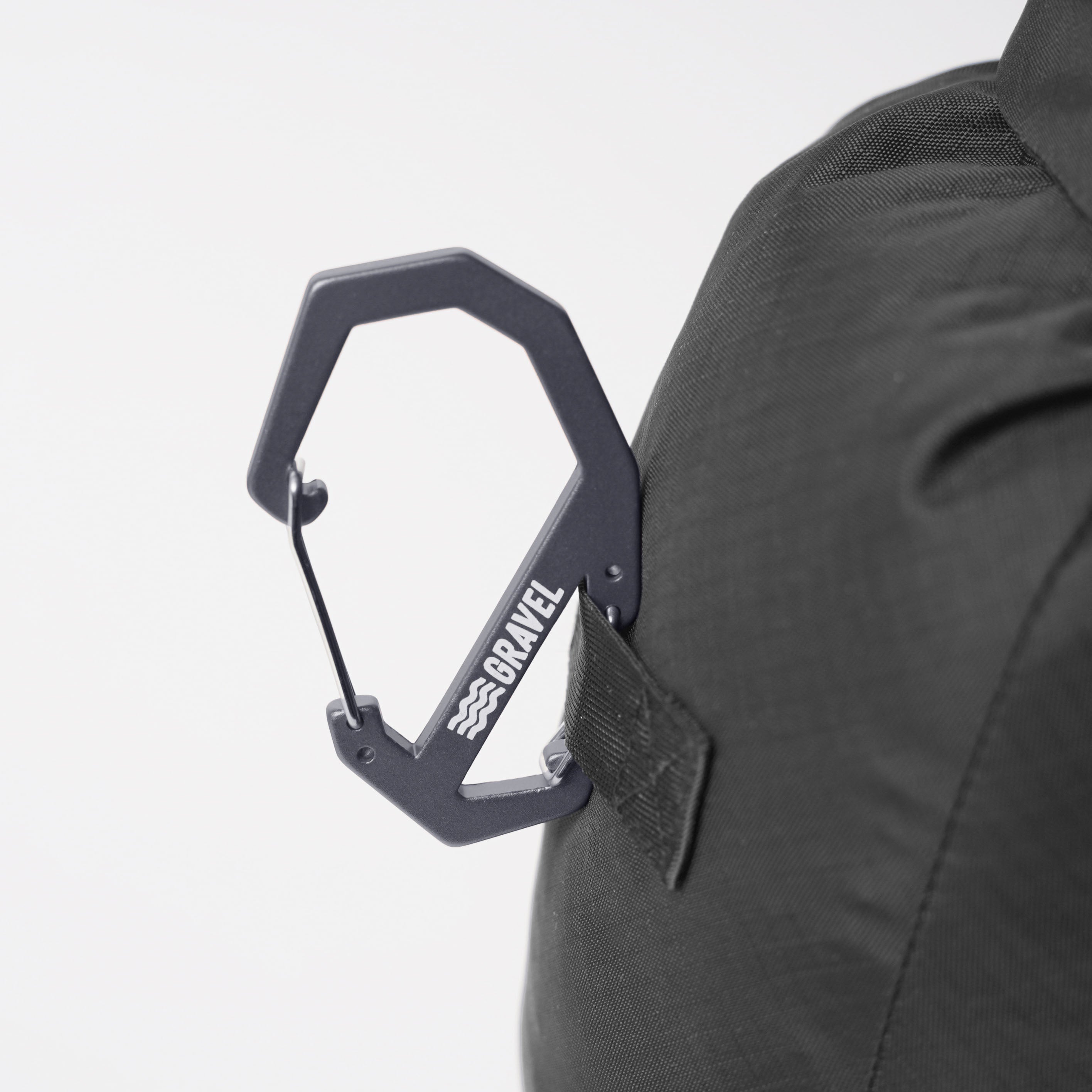 Black carabiner with 'Bravel' logo attached to a black backpack on a white background