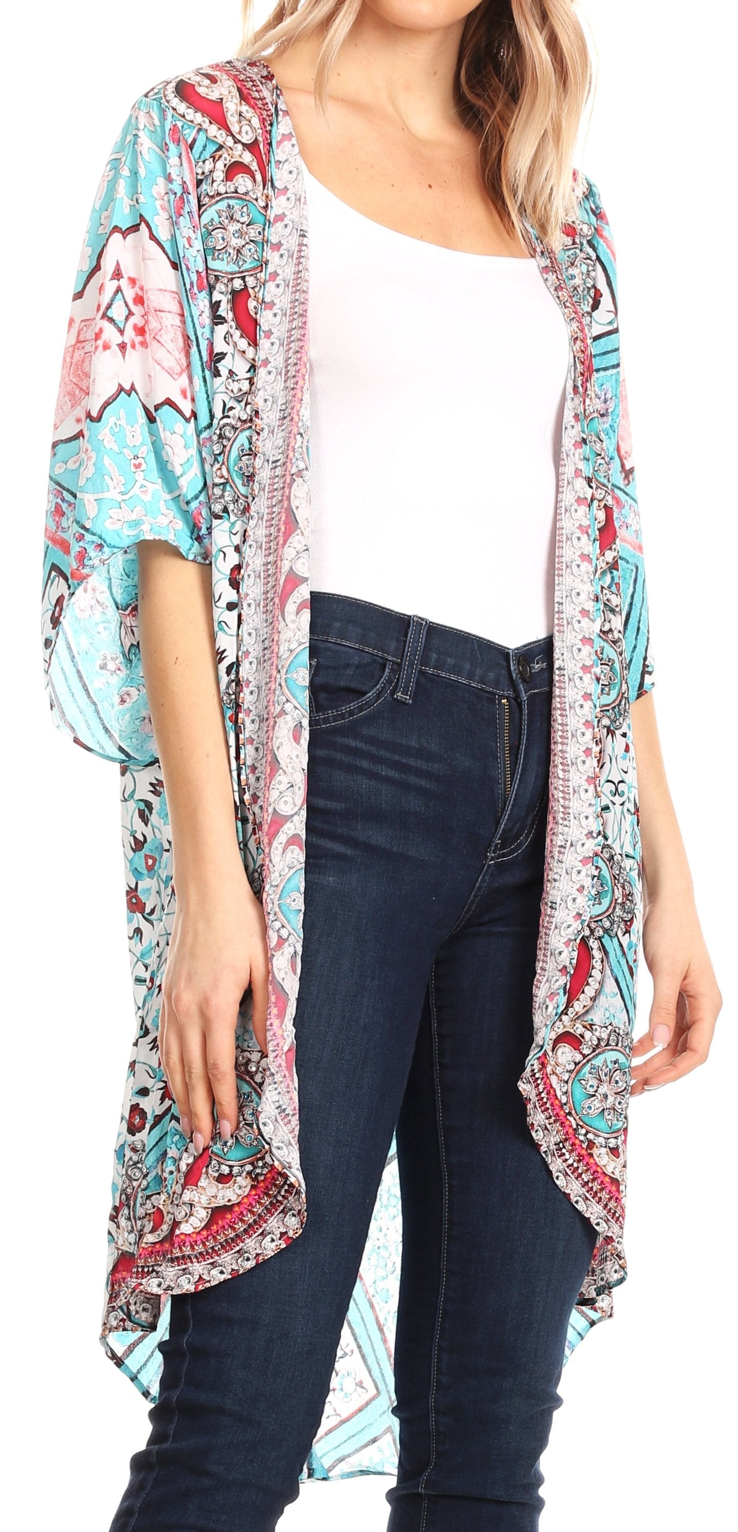 Woman wearing a colorful patterned kimono over a white top and dark jeans on a white background