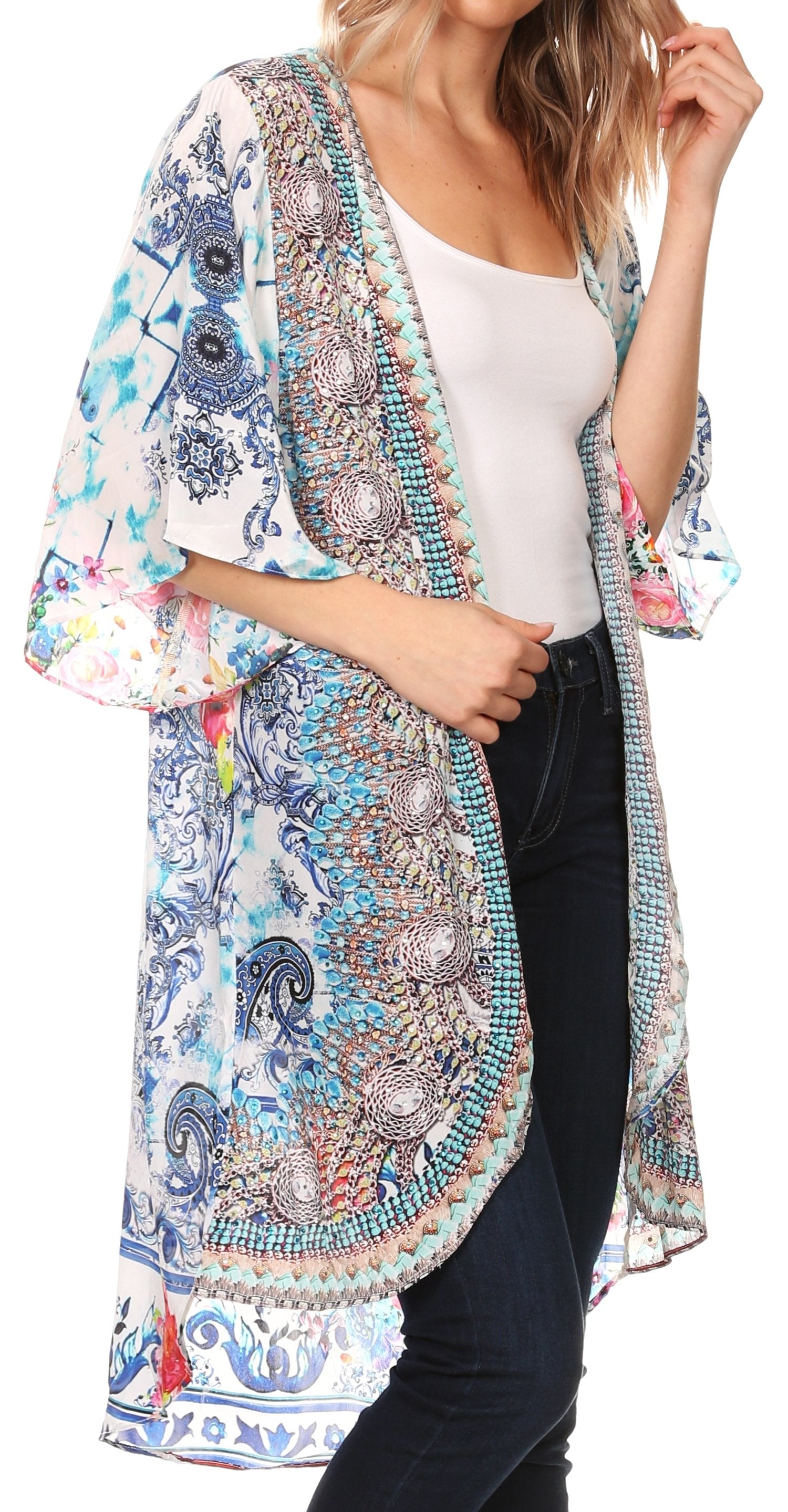 Woman wearing a colorful patterned kimono over a white top and black pants on a white background