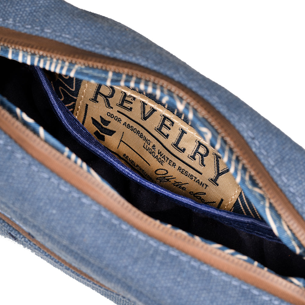 Close-up of a blue denim pouch with a brown label featuring the brand 'Revelry'.