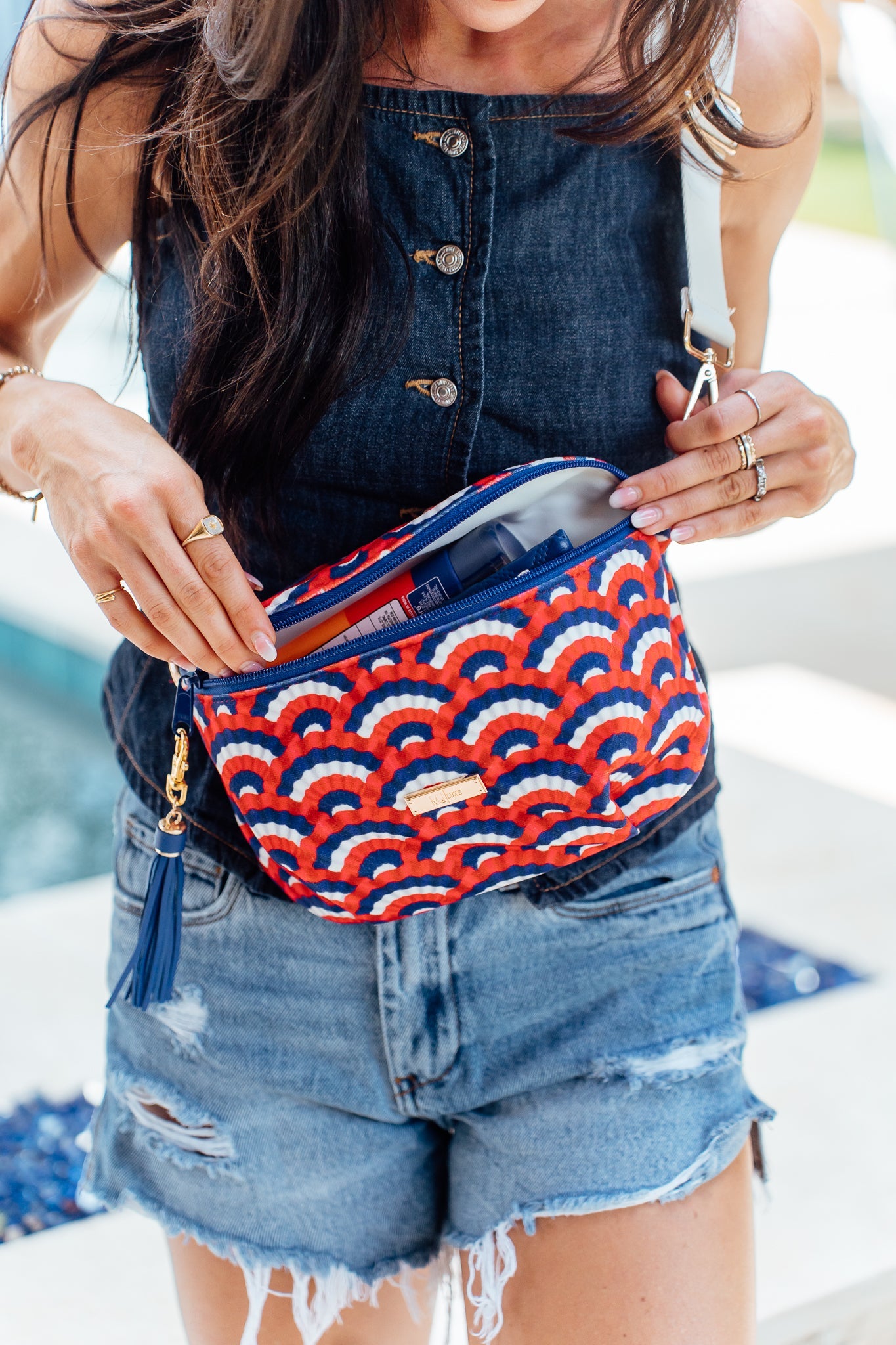 Person wearing a red and blue patterned waist bag with denim shorts.