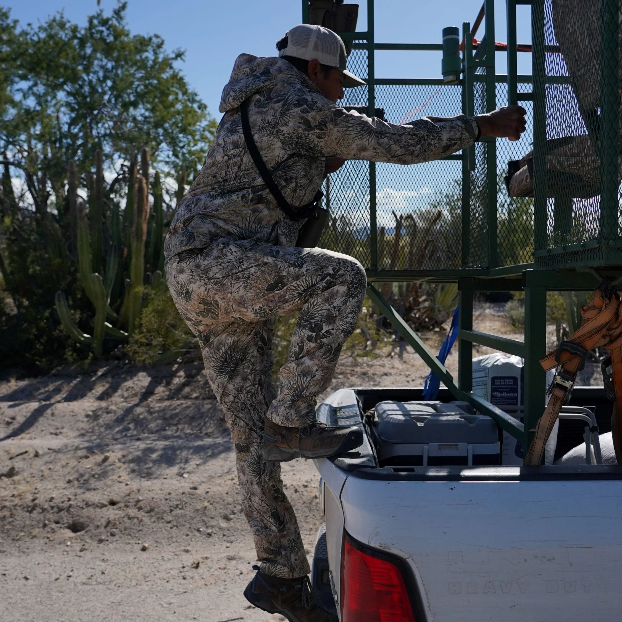 Person in camouflage climbing into a vehicle with a desert landscape in the background