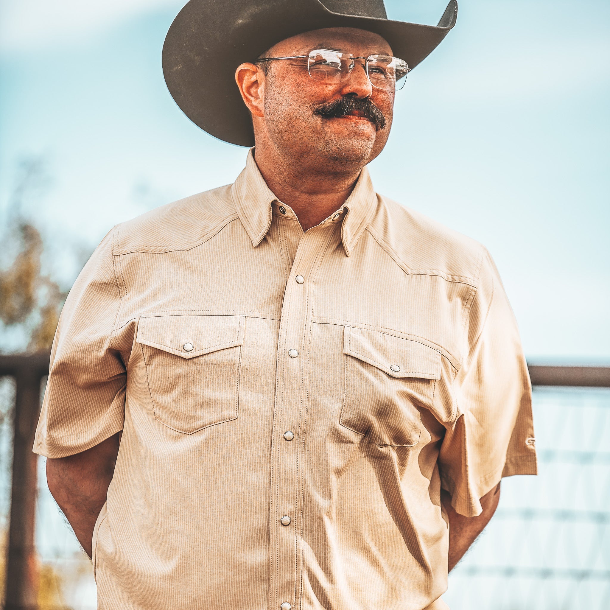 Man wearing a beige shirt and cowboy hat with a blurred background