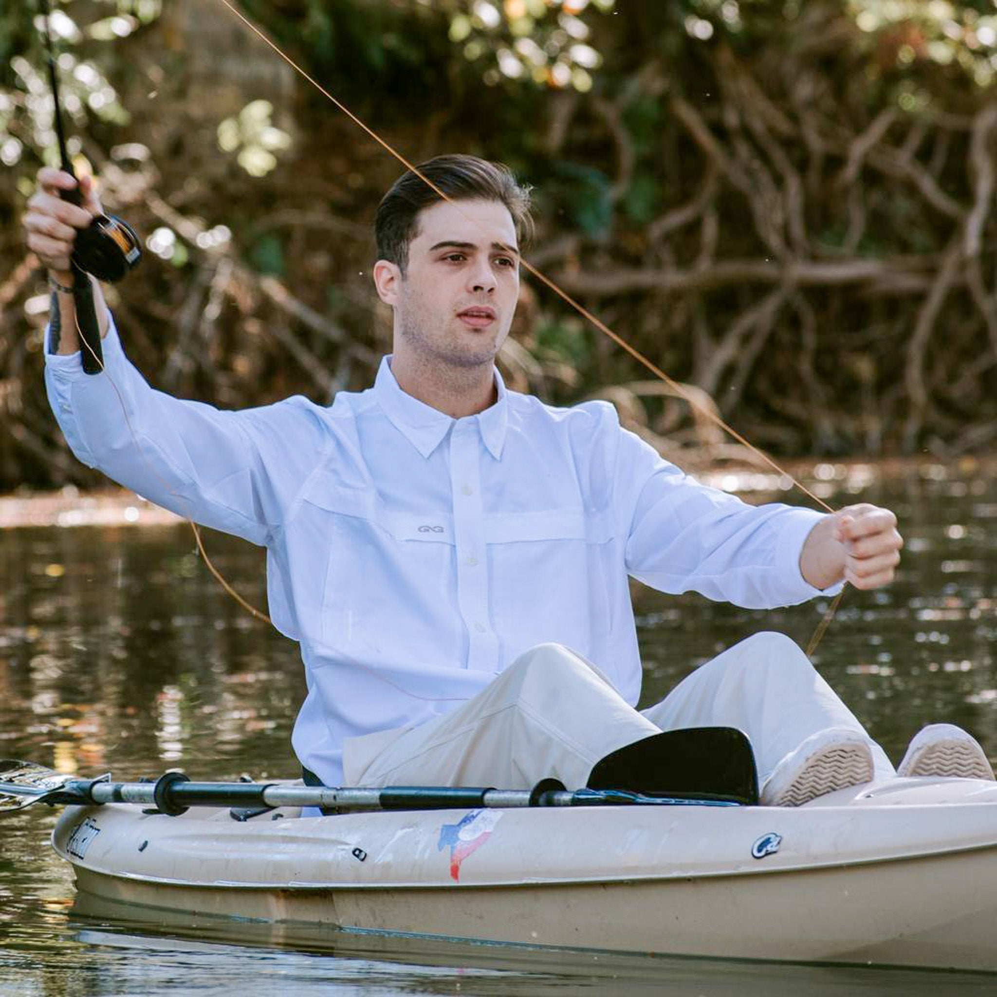 Man in a kayak on a body of water with trees in the background