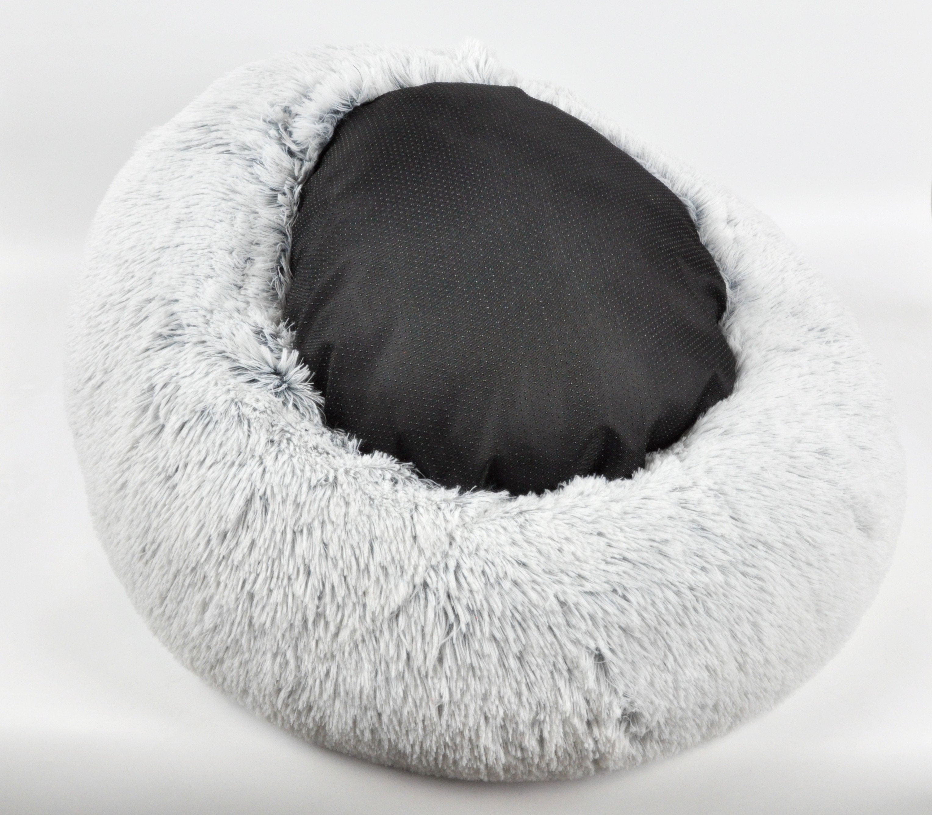 Gray fluffy pet bed with a black pillow on a white background