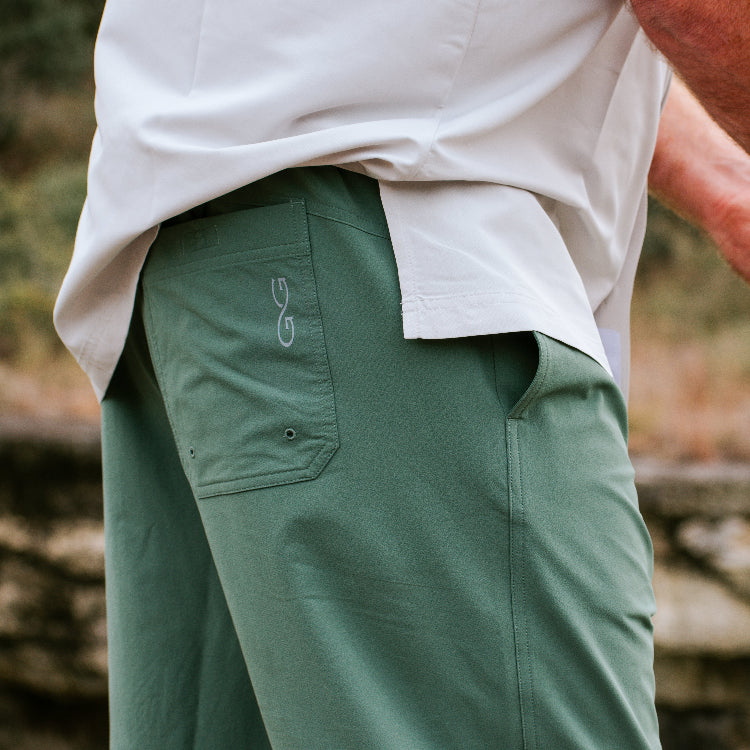 Person wearing green pants with a blurred natural background