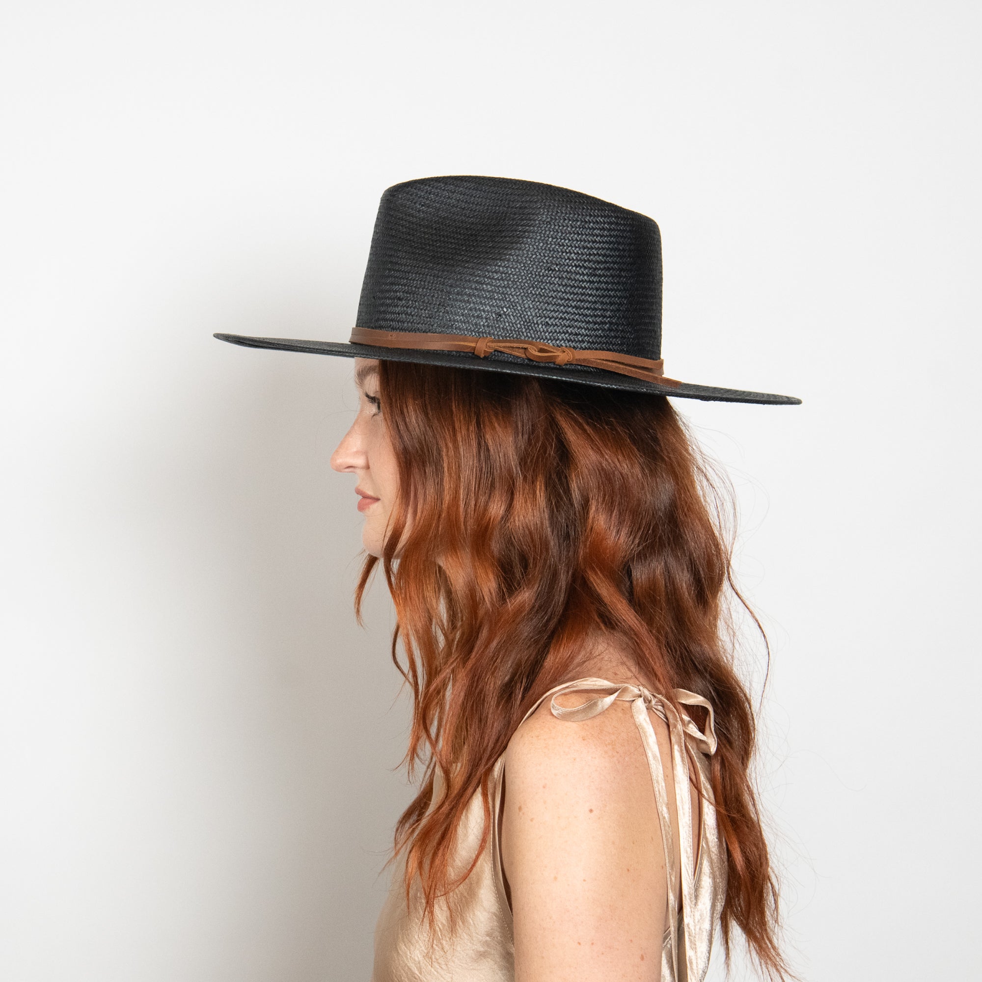 Woman wearing a black straw hat with a brown band on a white background
