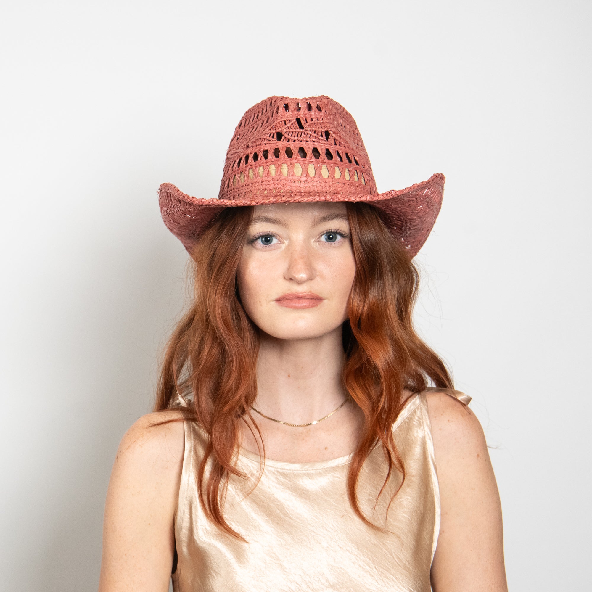 Woman wearing a red straw hat against a plain background