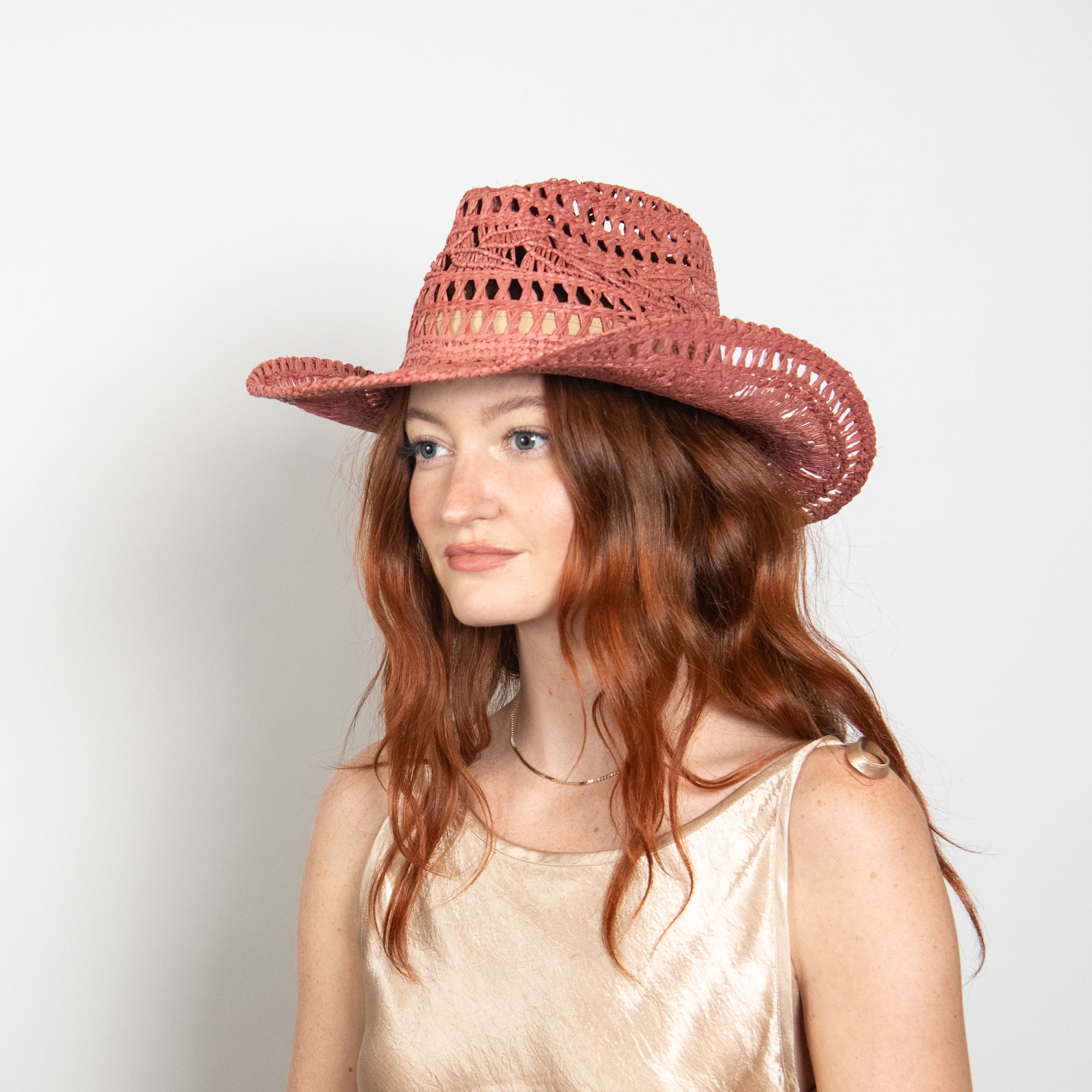 Woman wearing a red straw hat against a plain background