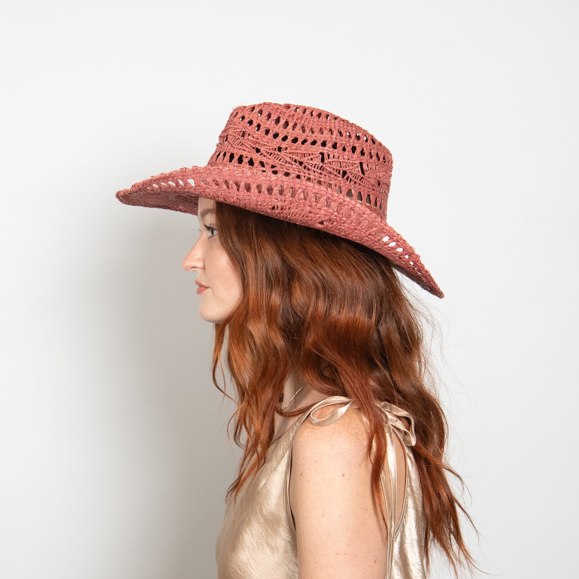 Woman wearing a pink straw hat against a plain background