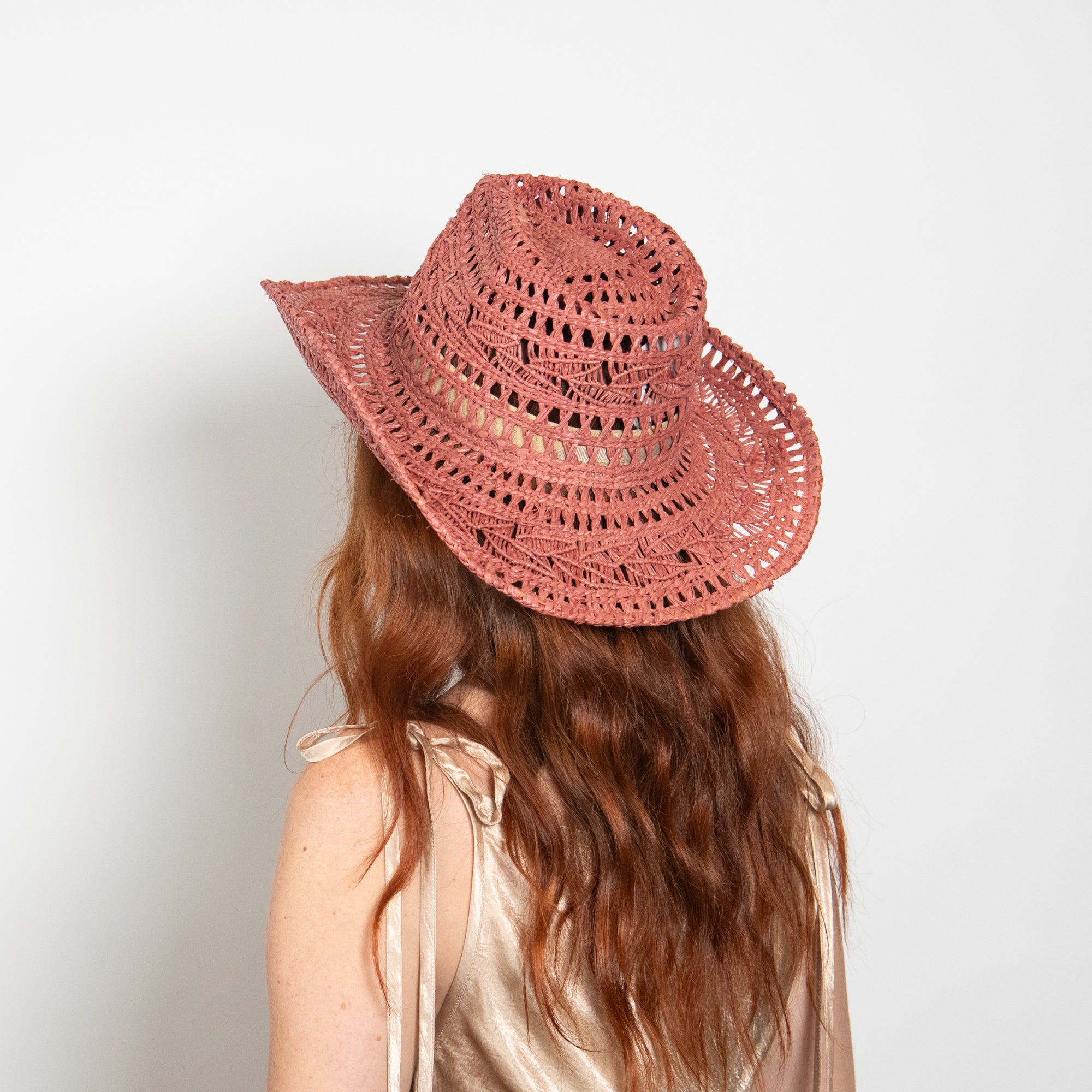 Person wearing a pink straw hat on a plain background