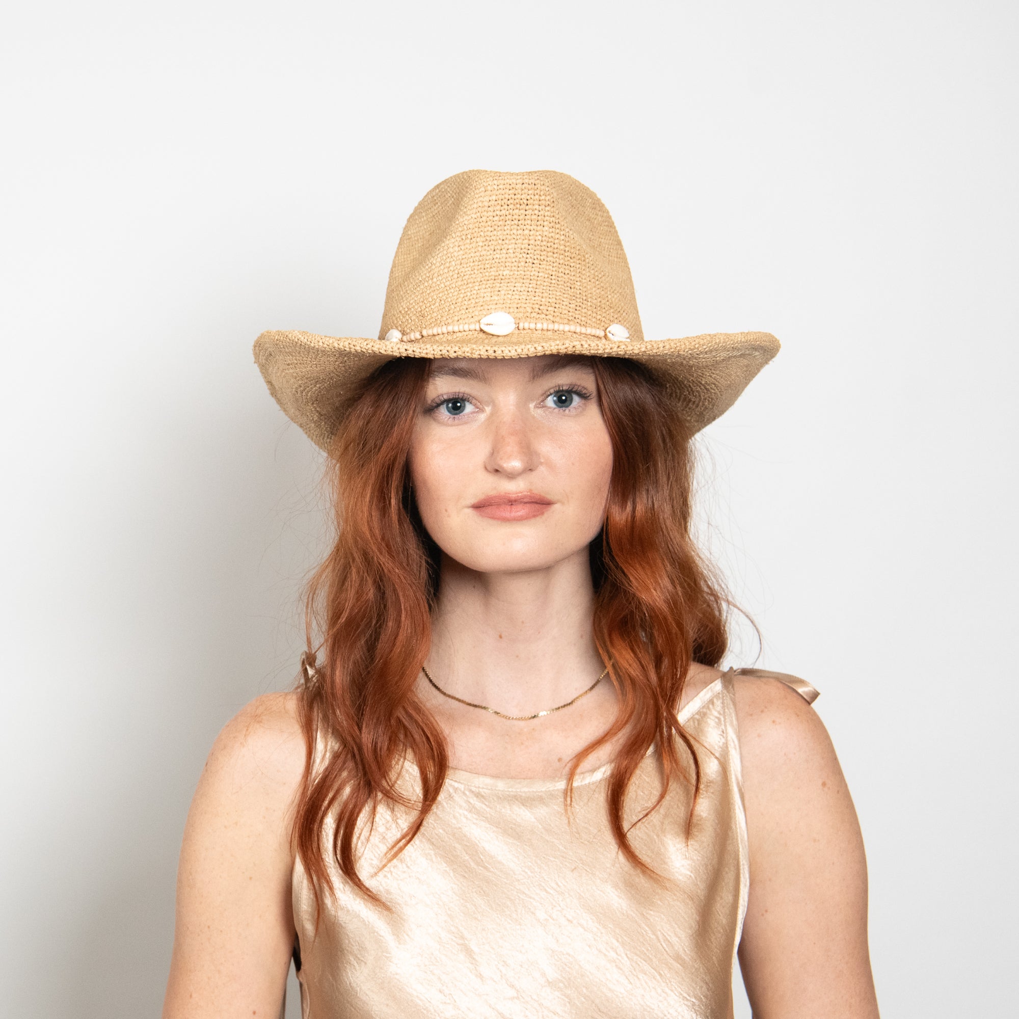 Woman wearing a straw hat against a plain background