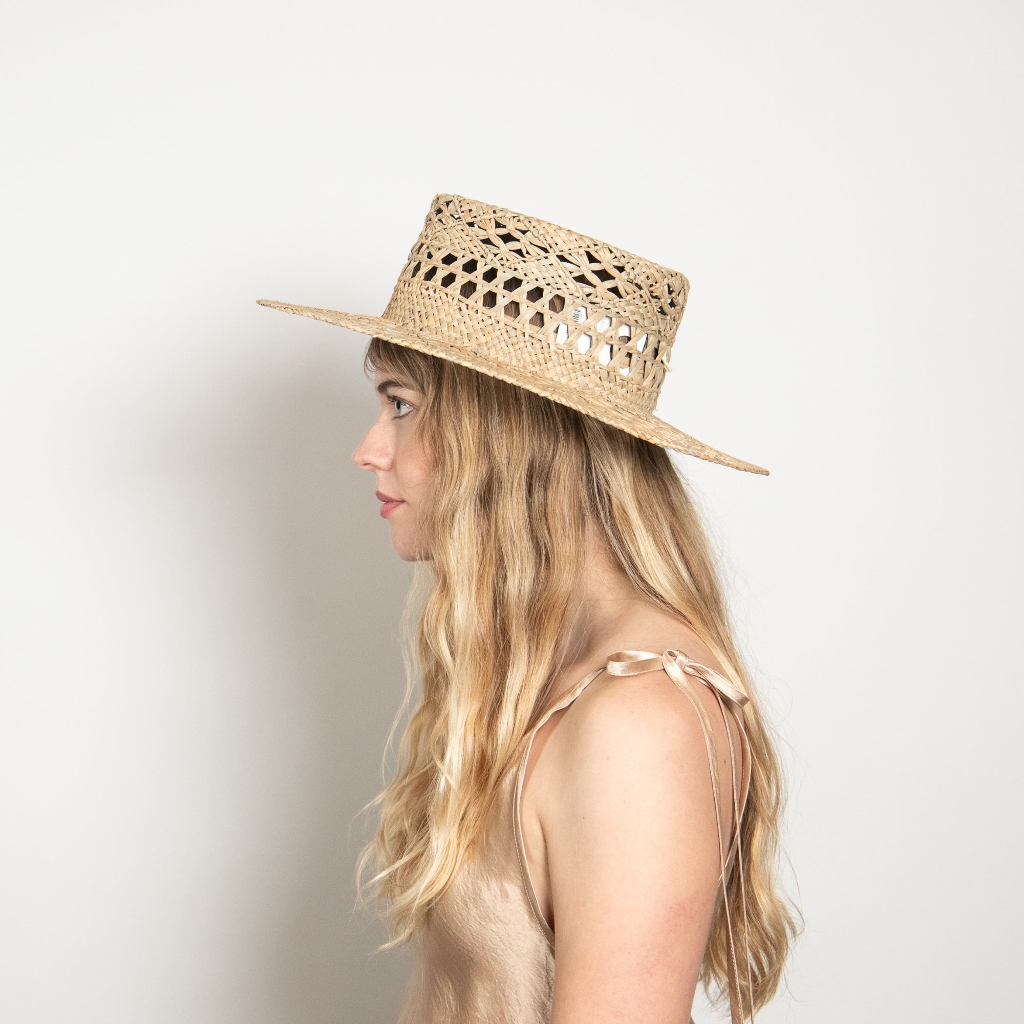 Woman wearing a straw hat against a plain background