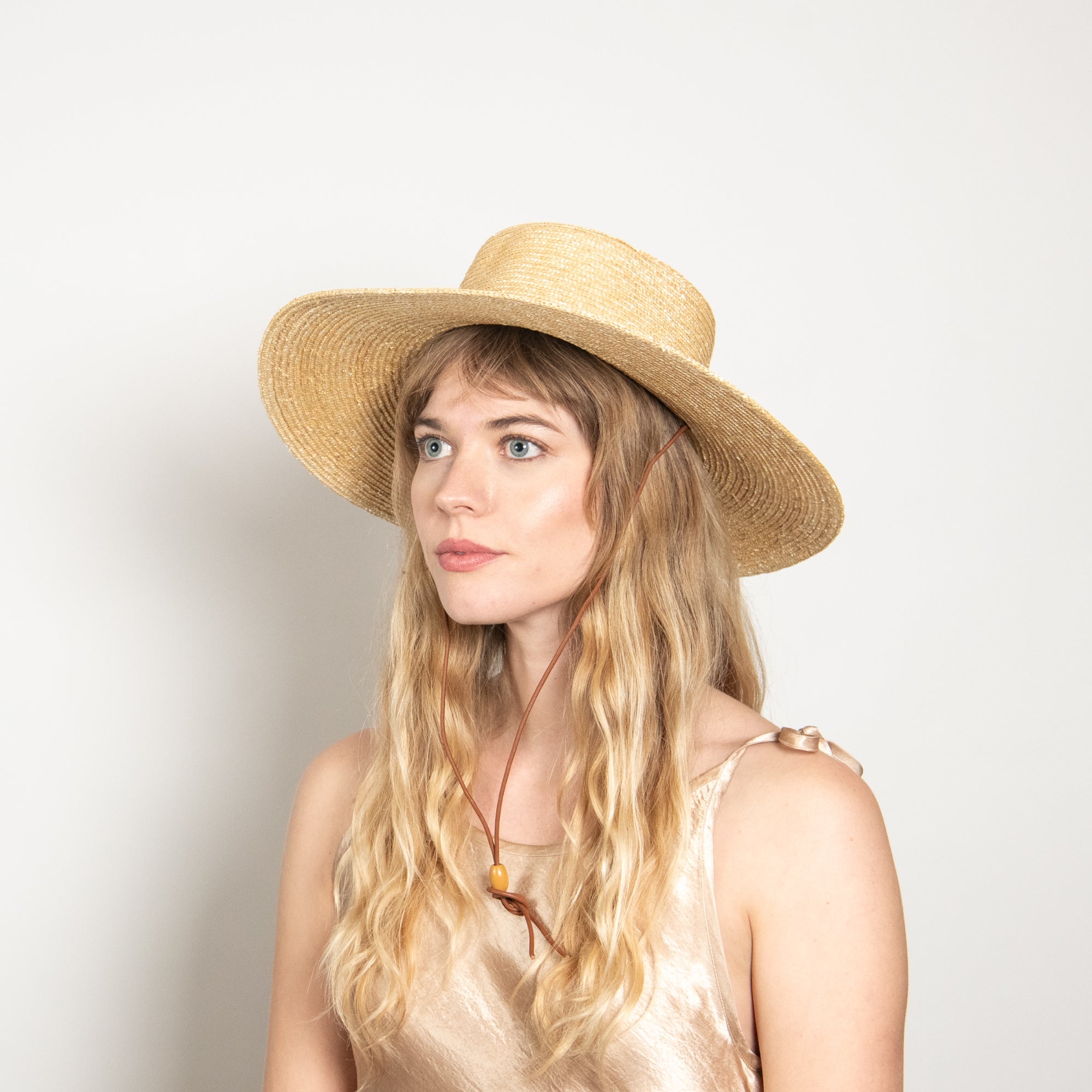 Woman wearing a straw hat against a plain background