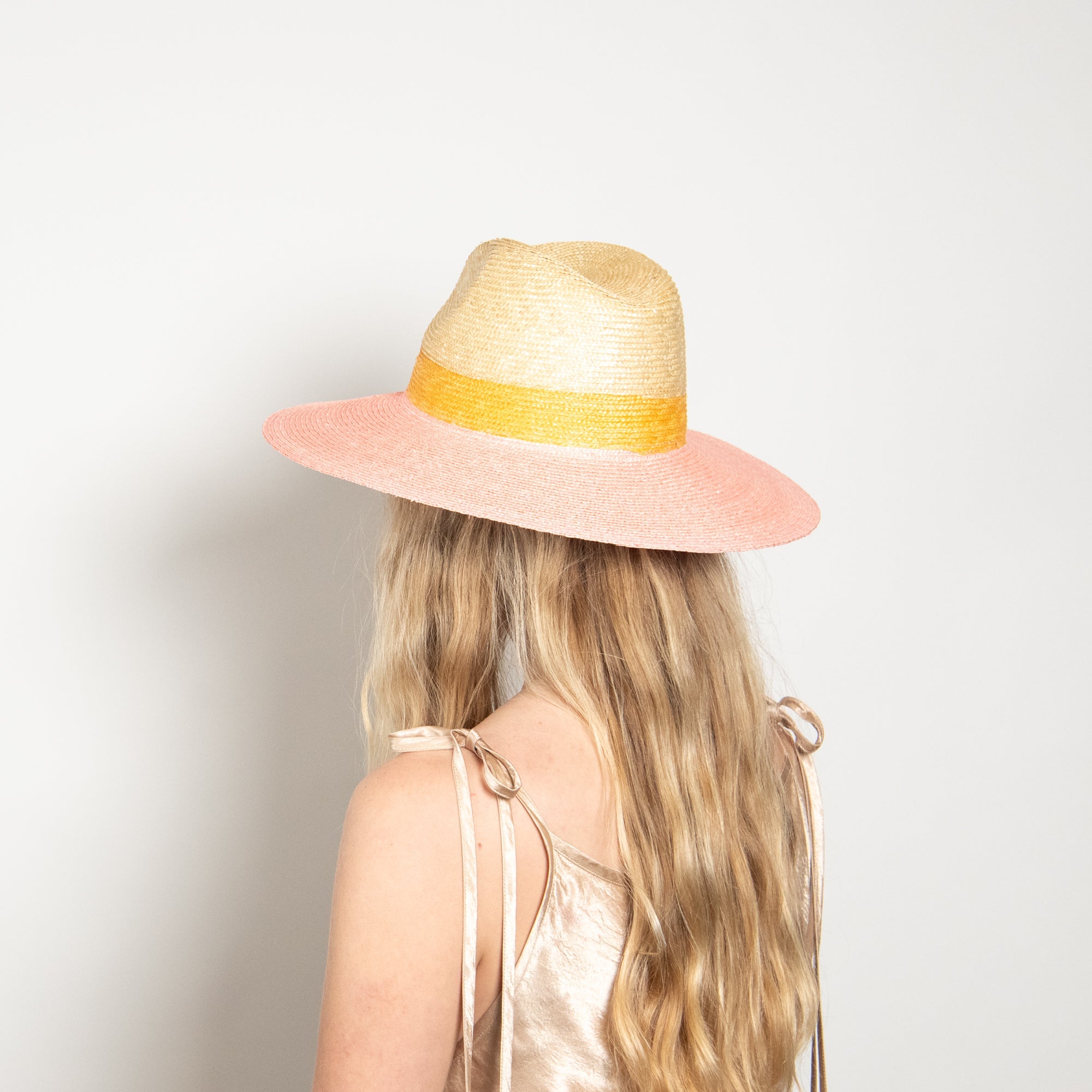 Person wearing a colorful straw hat with a plain background