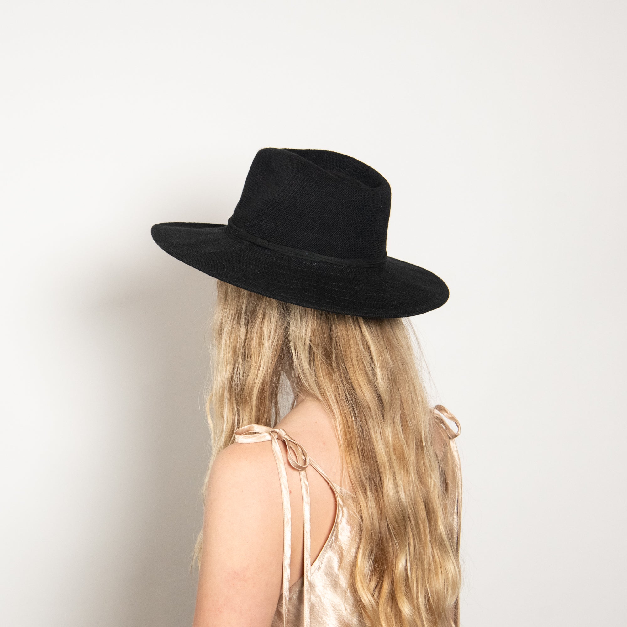 Person wearing a black hat with a plain background