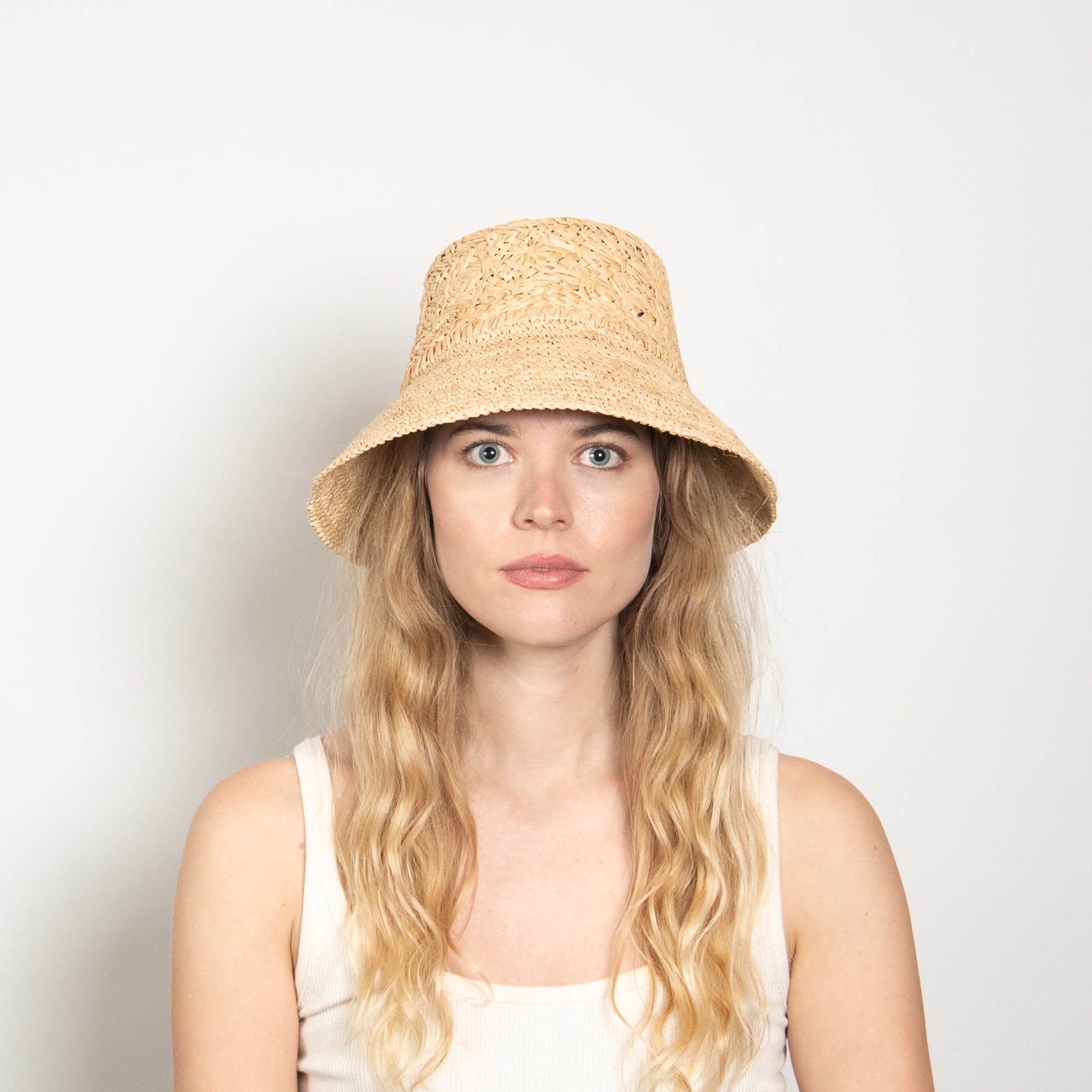 Woman wearing a straw hat against a plain background