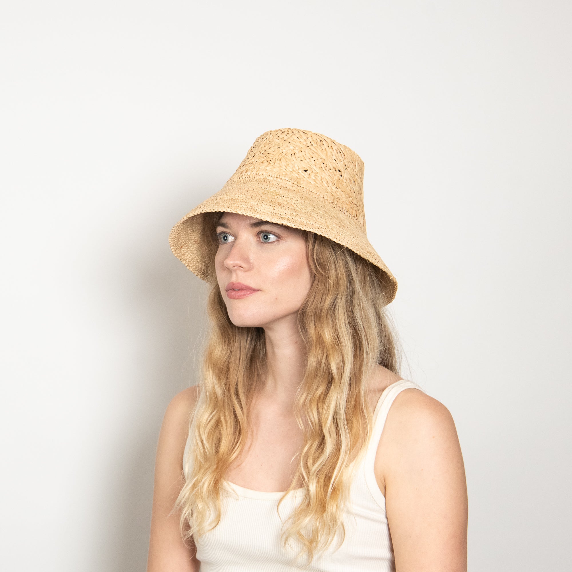 Woman wearing a straw hat against a plain background