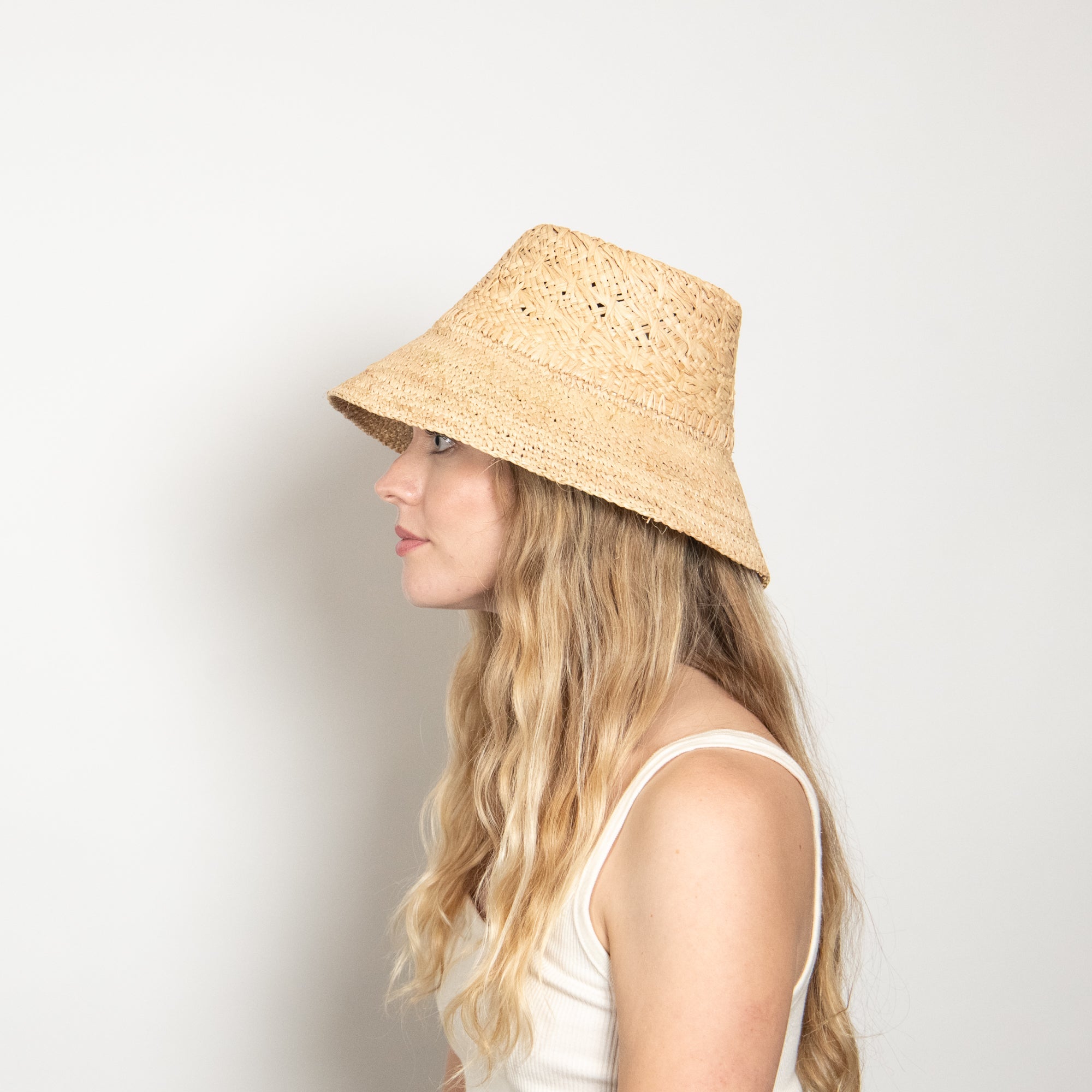 Woman wearing a straw bucket hat on a plain background