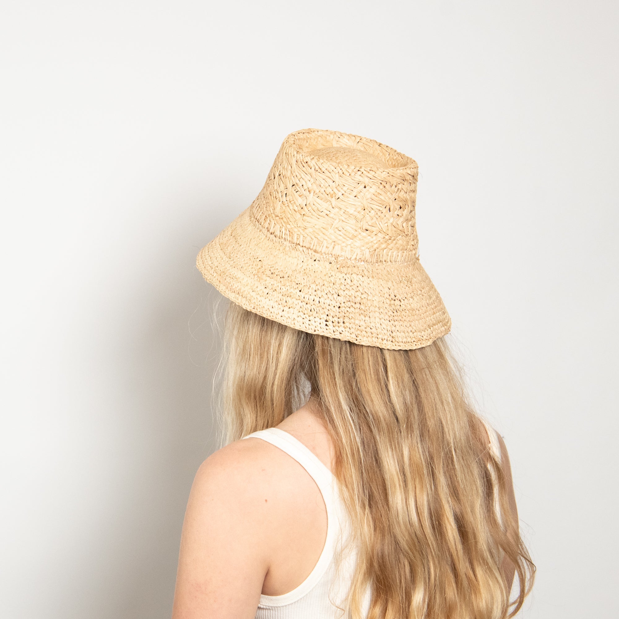Person wearing a straw bucket hat against a plain background