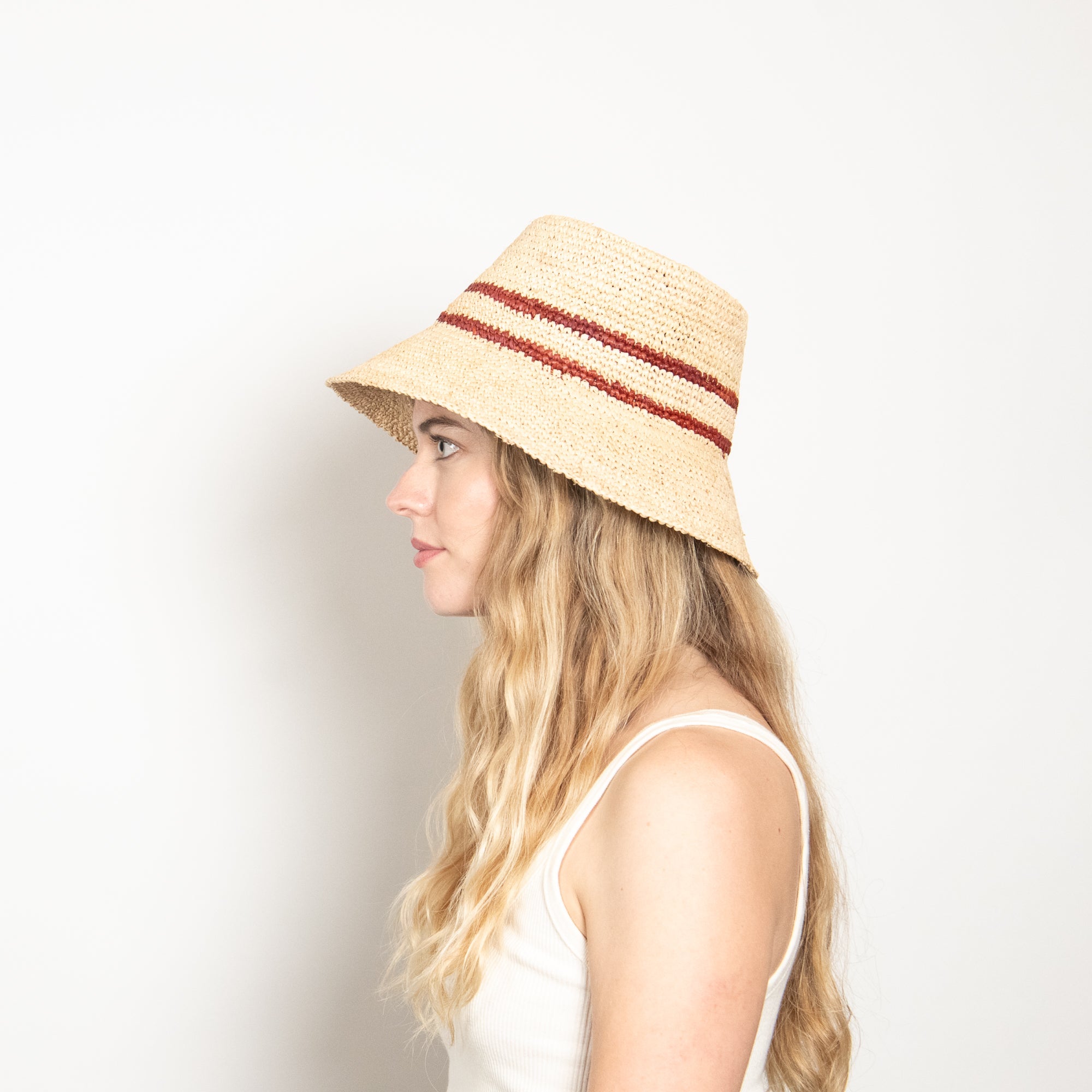 Woman wearing a straw hat with red band on a plain background