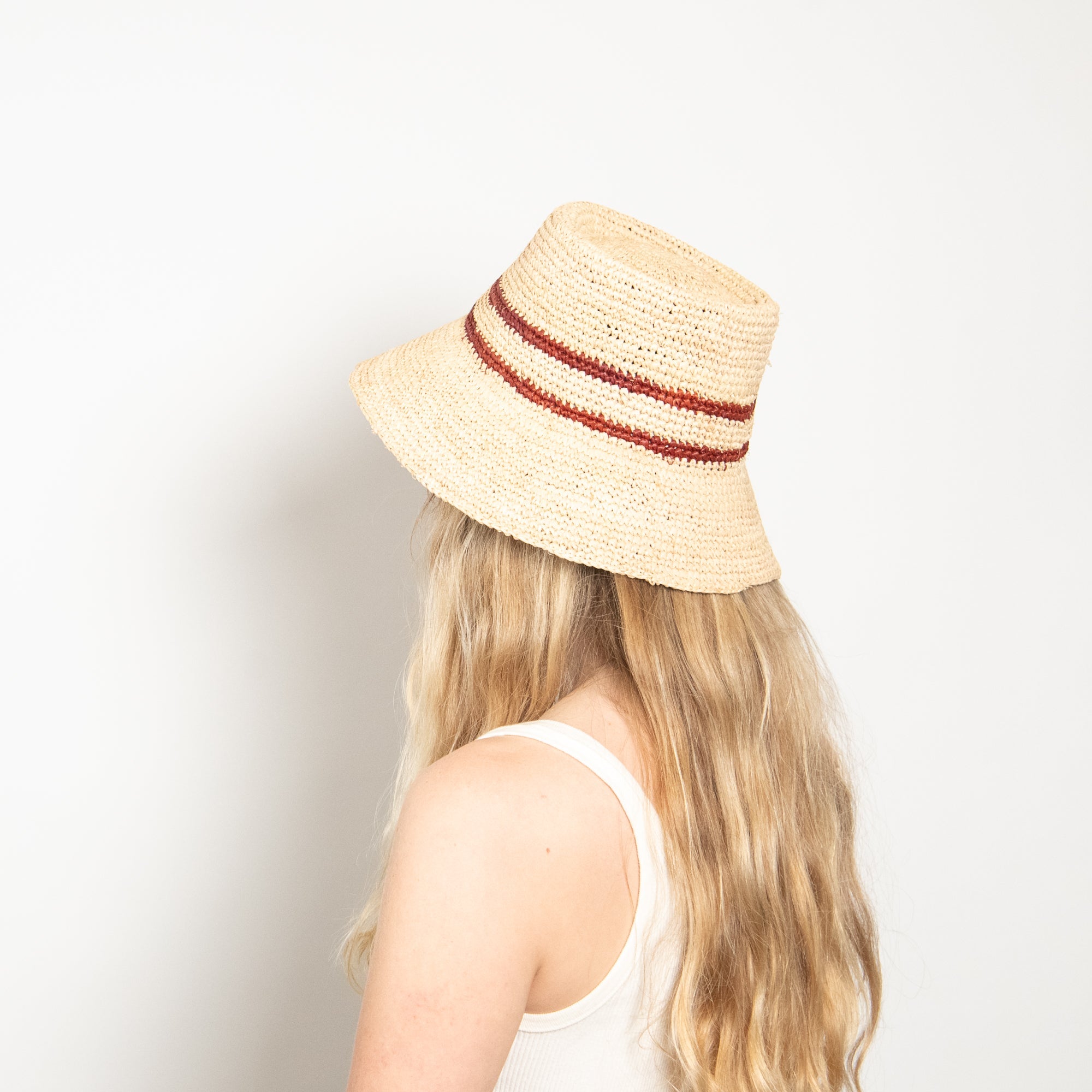 Person wearing a straw hat with red band on a plain background