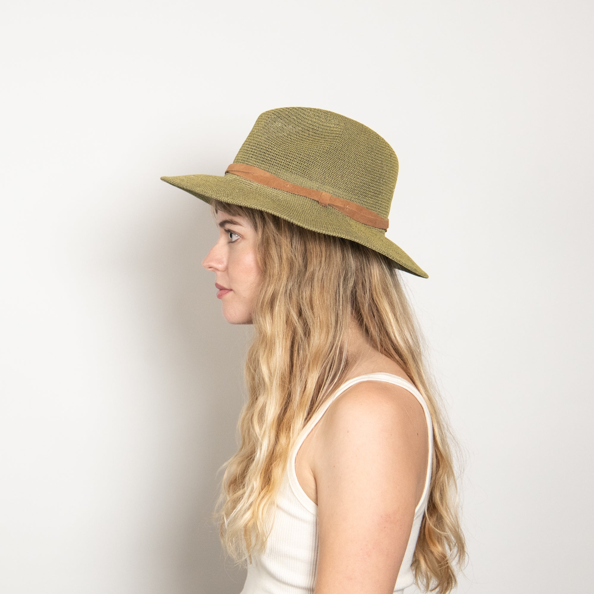 Woman wearing a green straw hat with a brown band on a white background