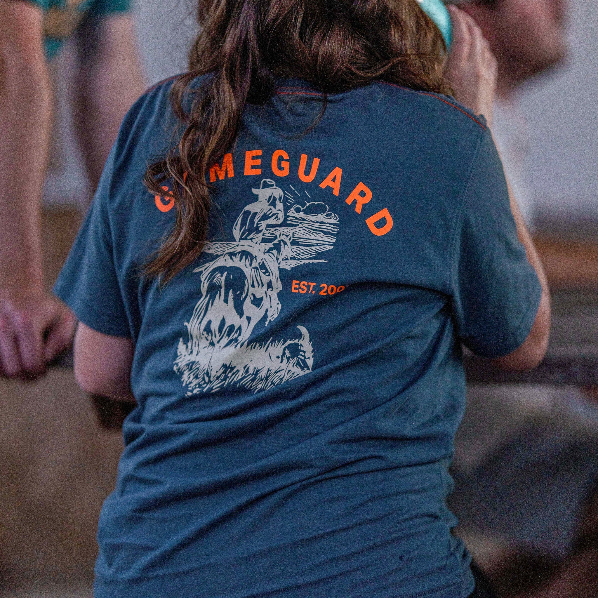 Person wearing a blue t-shirt with 'GameGuard' logo and text.