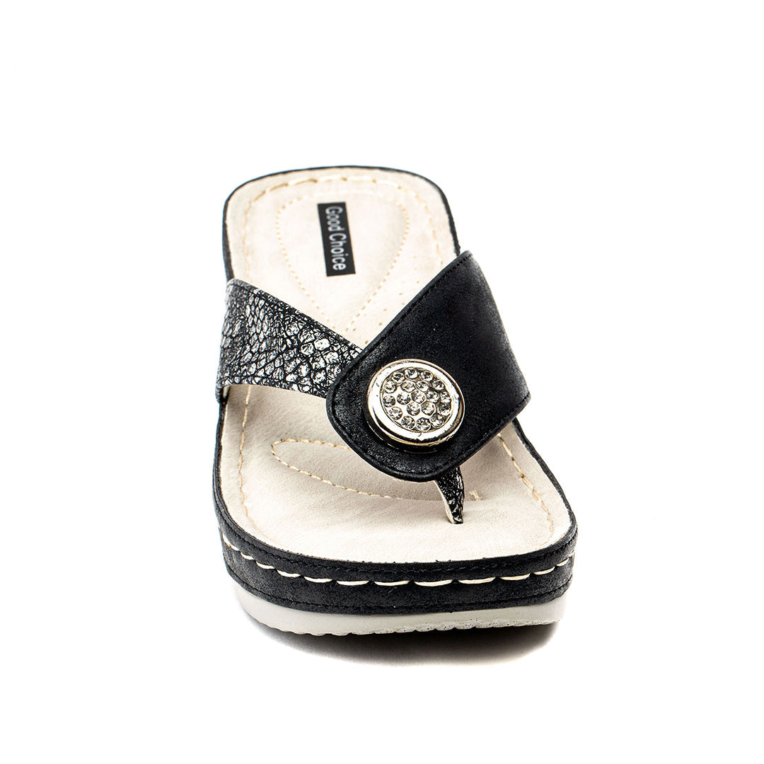 Black sandal with a decorative button on a white background