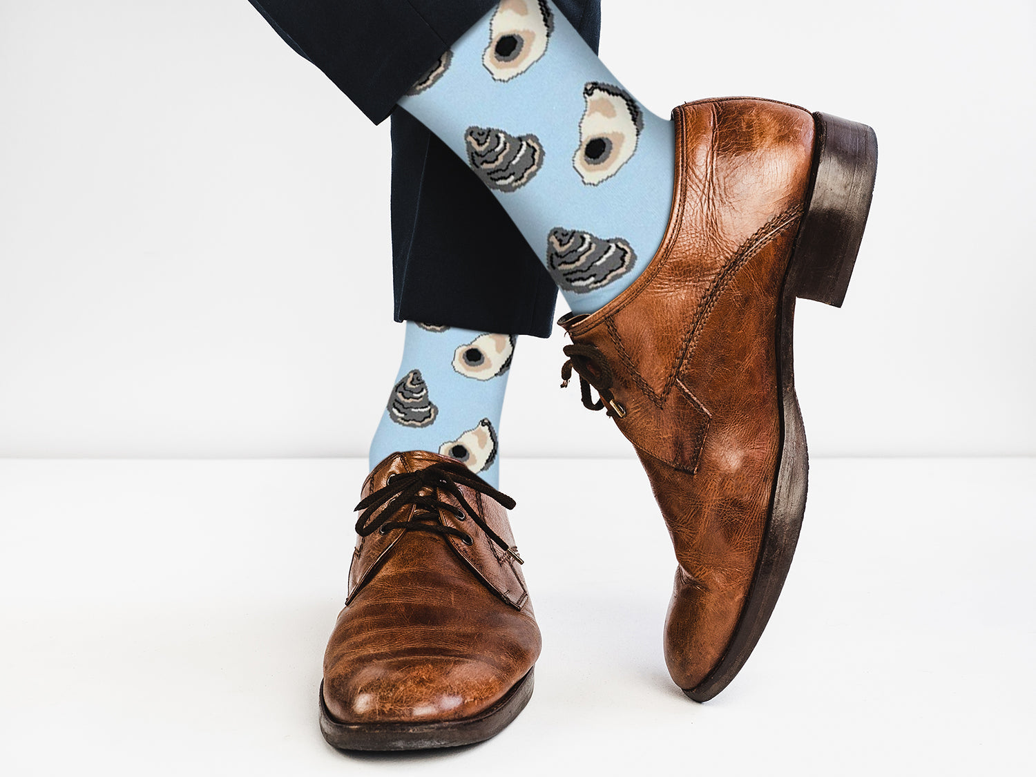 Brown dress shoes with blue socks featuring poop emoji design on a white background