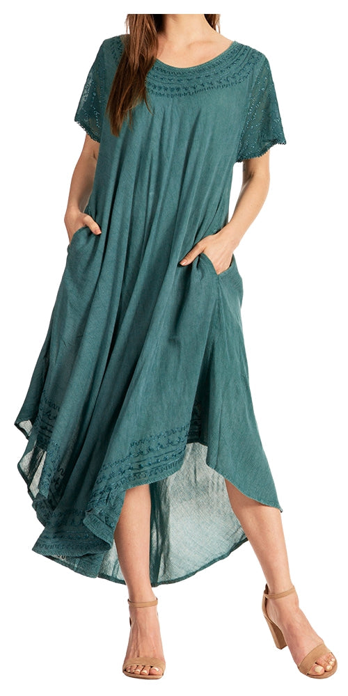 A woman wearing a teal blue-green high-low dress with short sleeves, side pockets, and lace detailing on the neckline and hem, paired with beige heeled sandals against a white background.