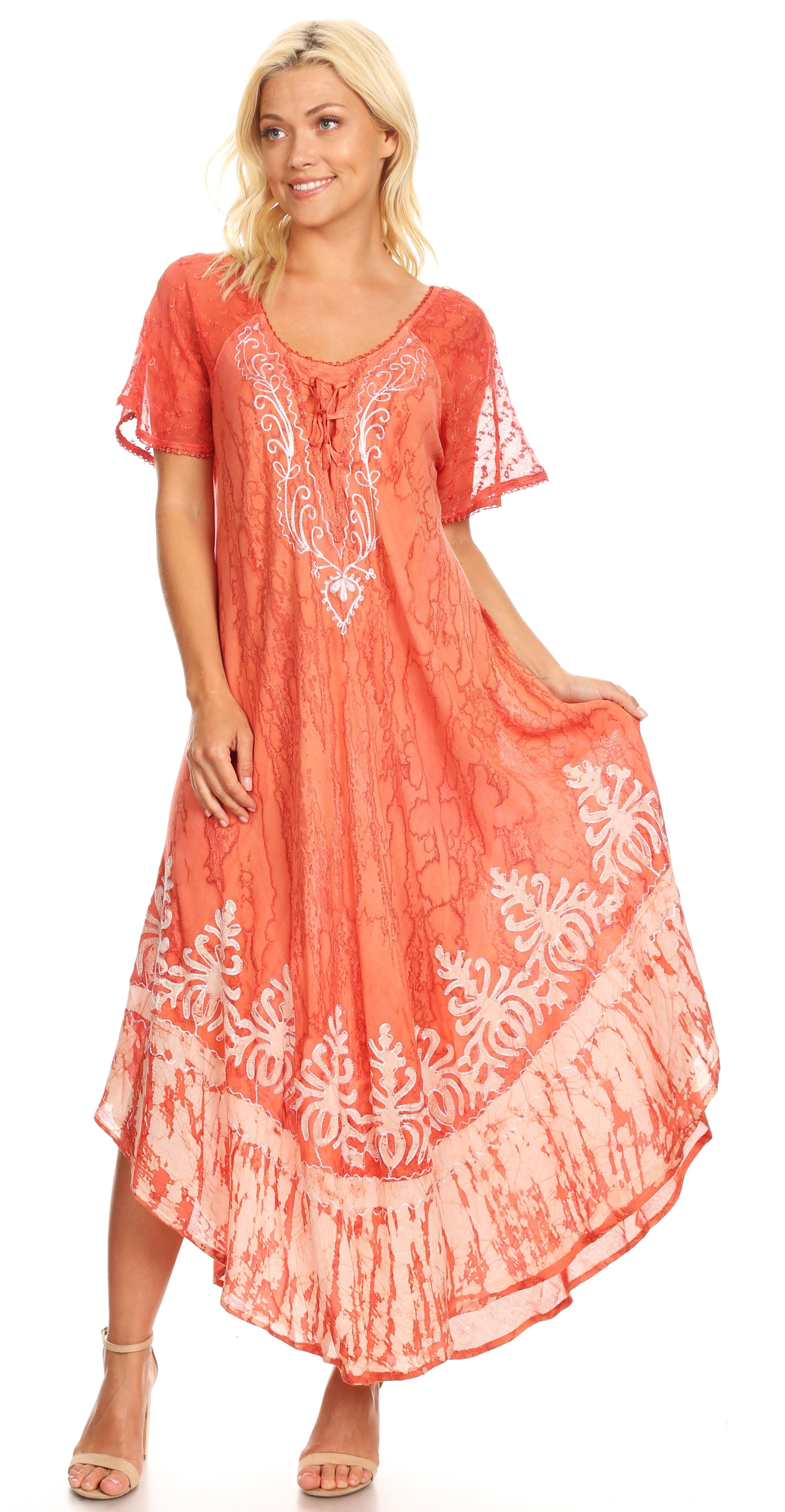 Woman wearing a coral dress with white embroidery on a white background