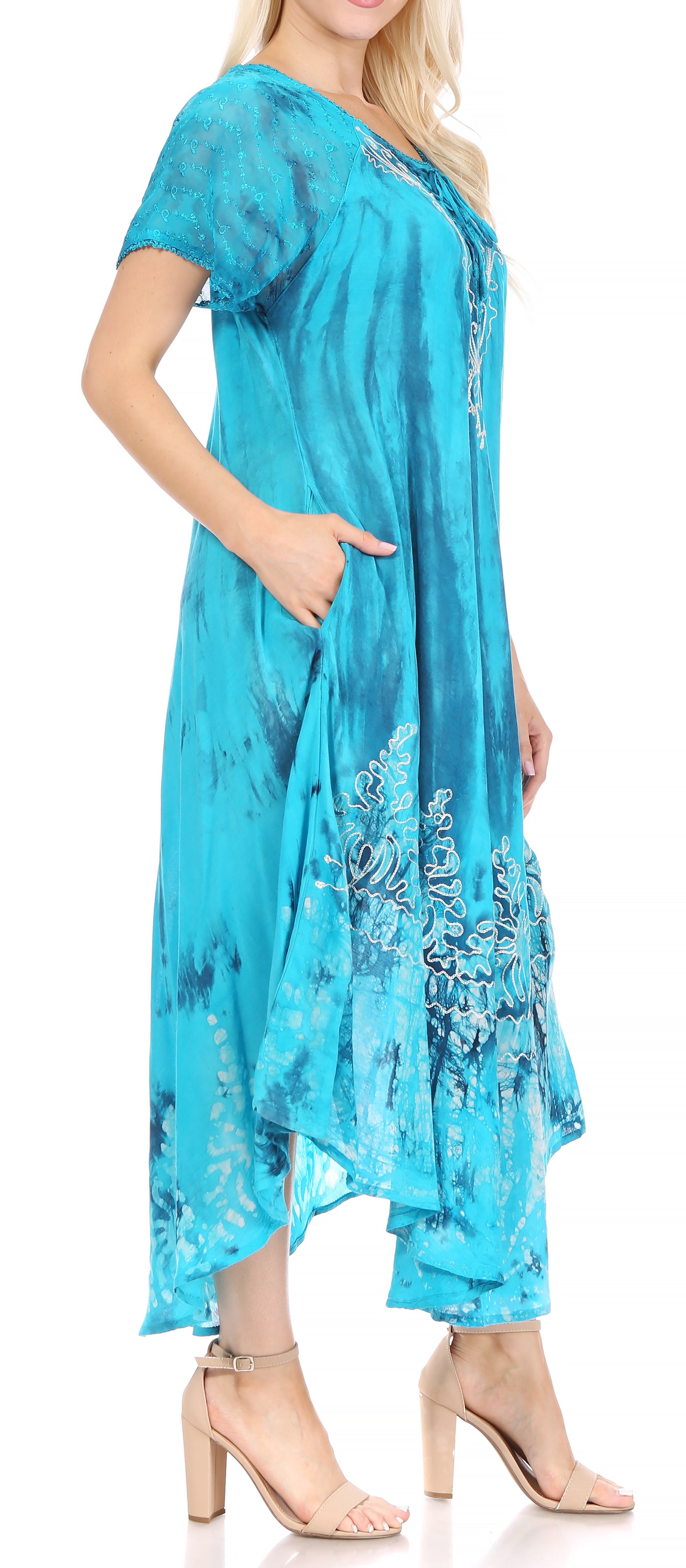 Woman wearing a turquoise dress with floral embroidery on a white background