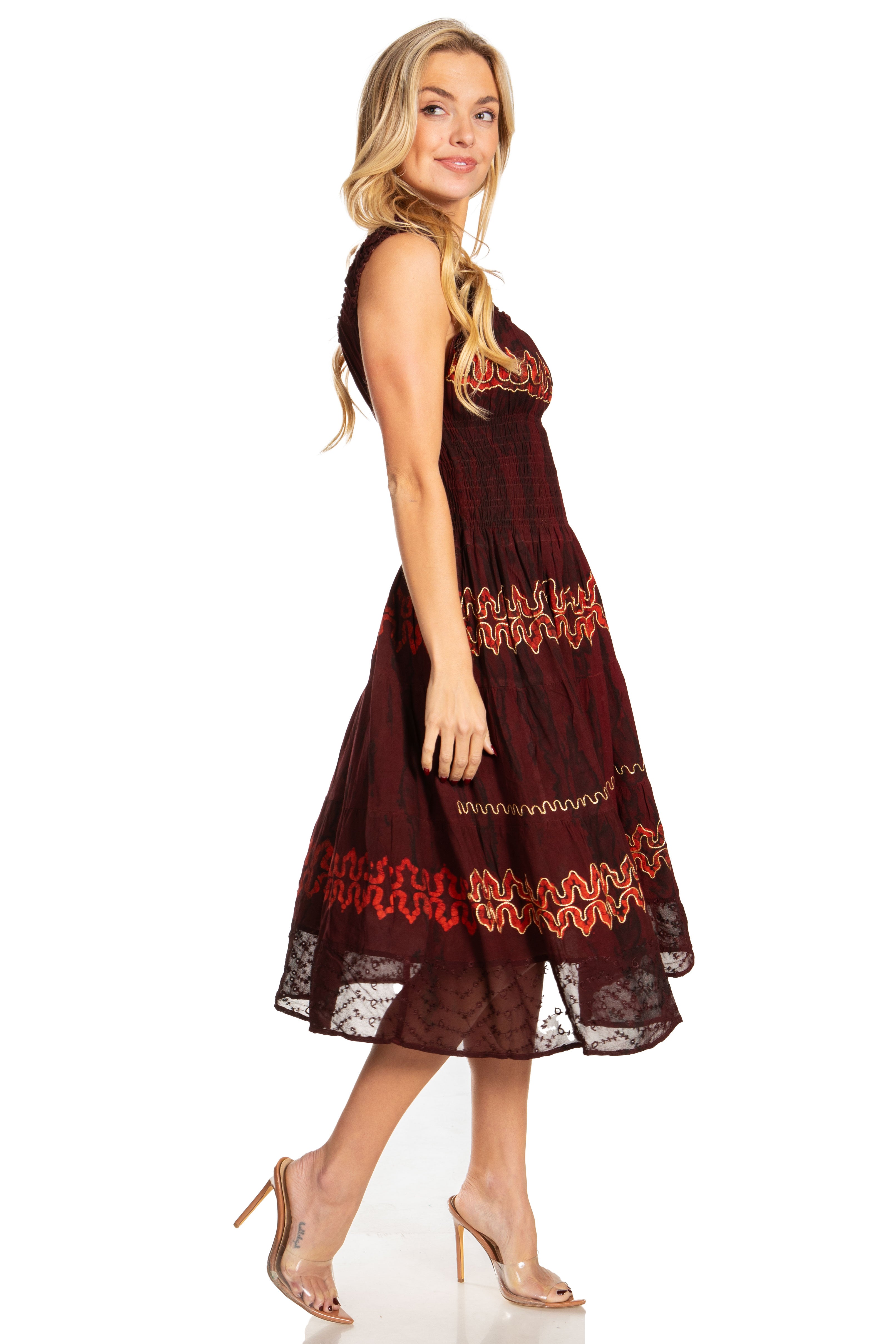 Woman wearing a brown dress with red floral embroidery on a white background