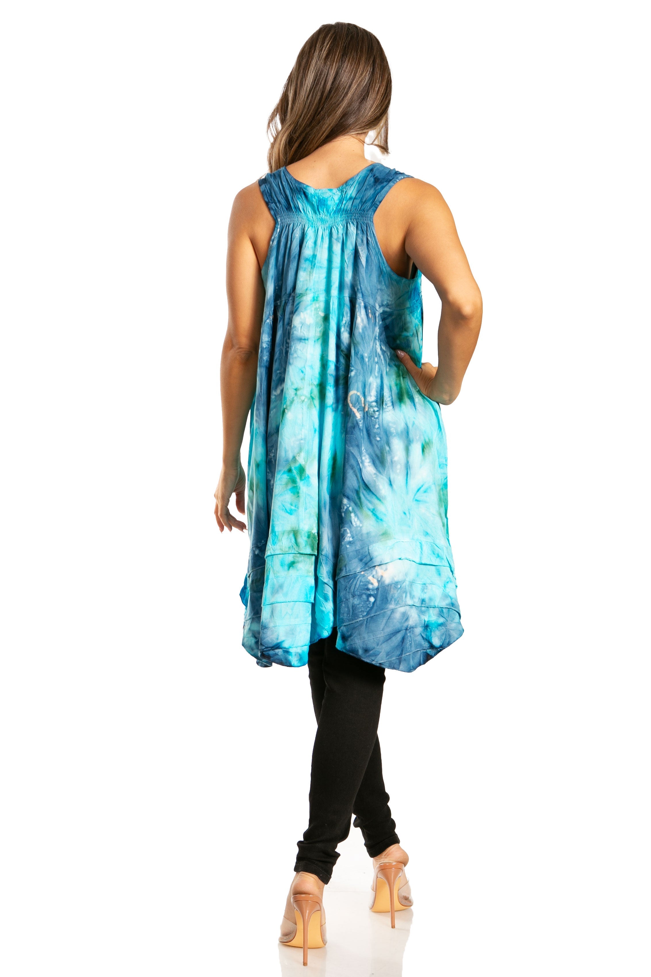 Woman wearing a blue tie-dye sleeveless top with black pants on a white background
