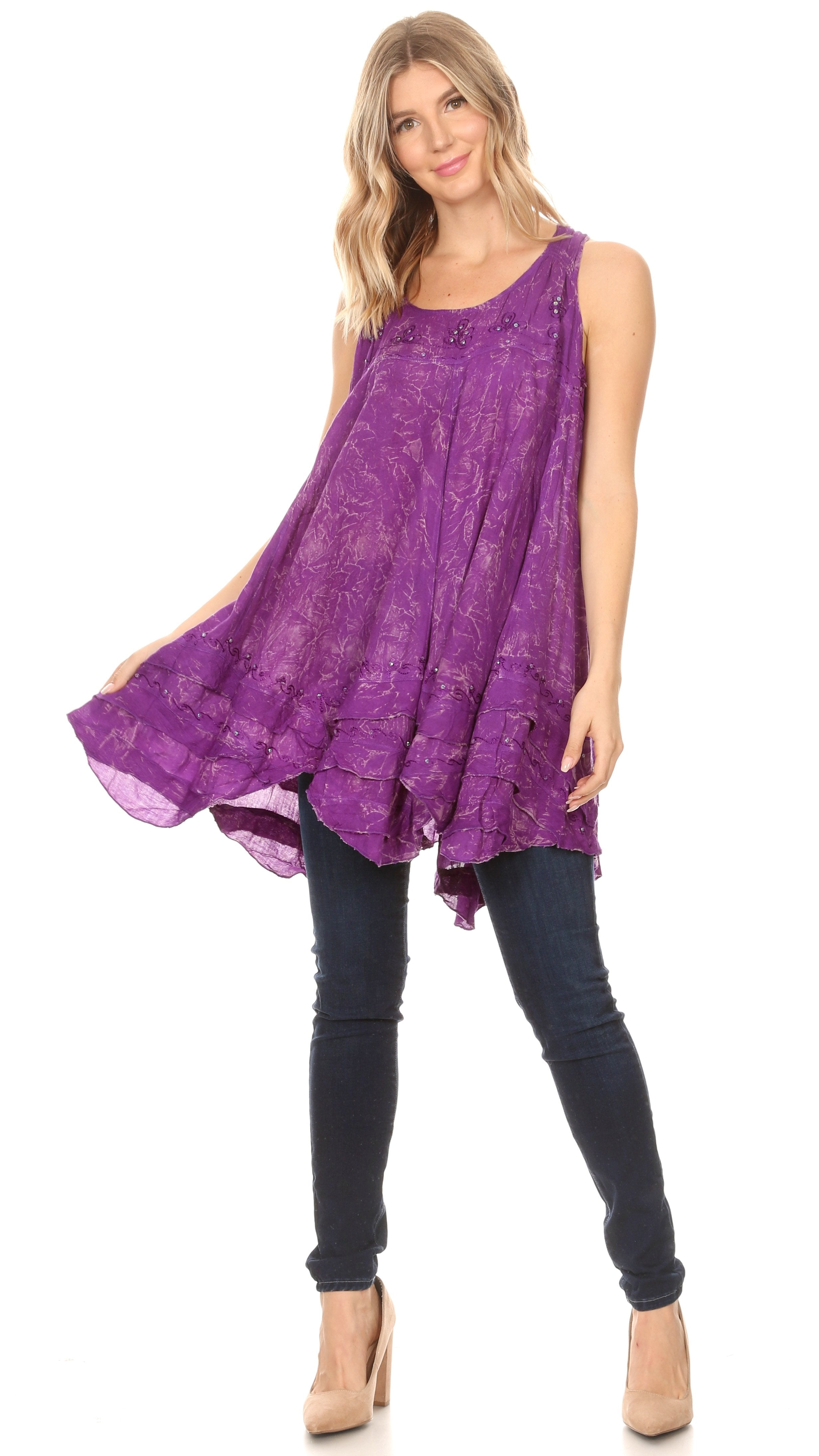 Woman wearing a purple patterned dress over black pants on a white background