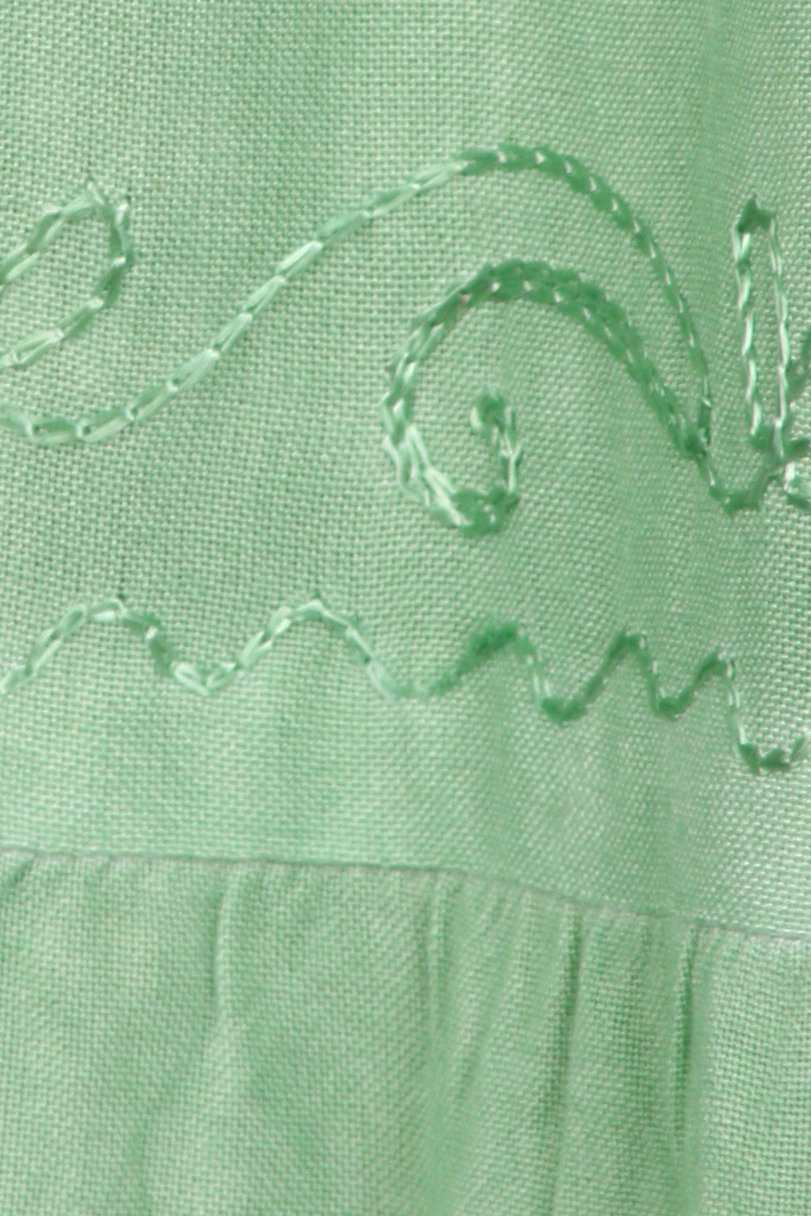 Close-up of a green fabric with embroidered patterns