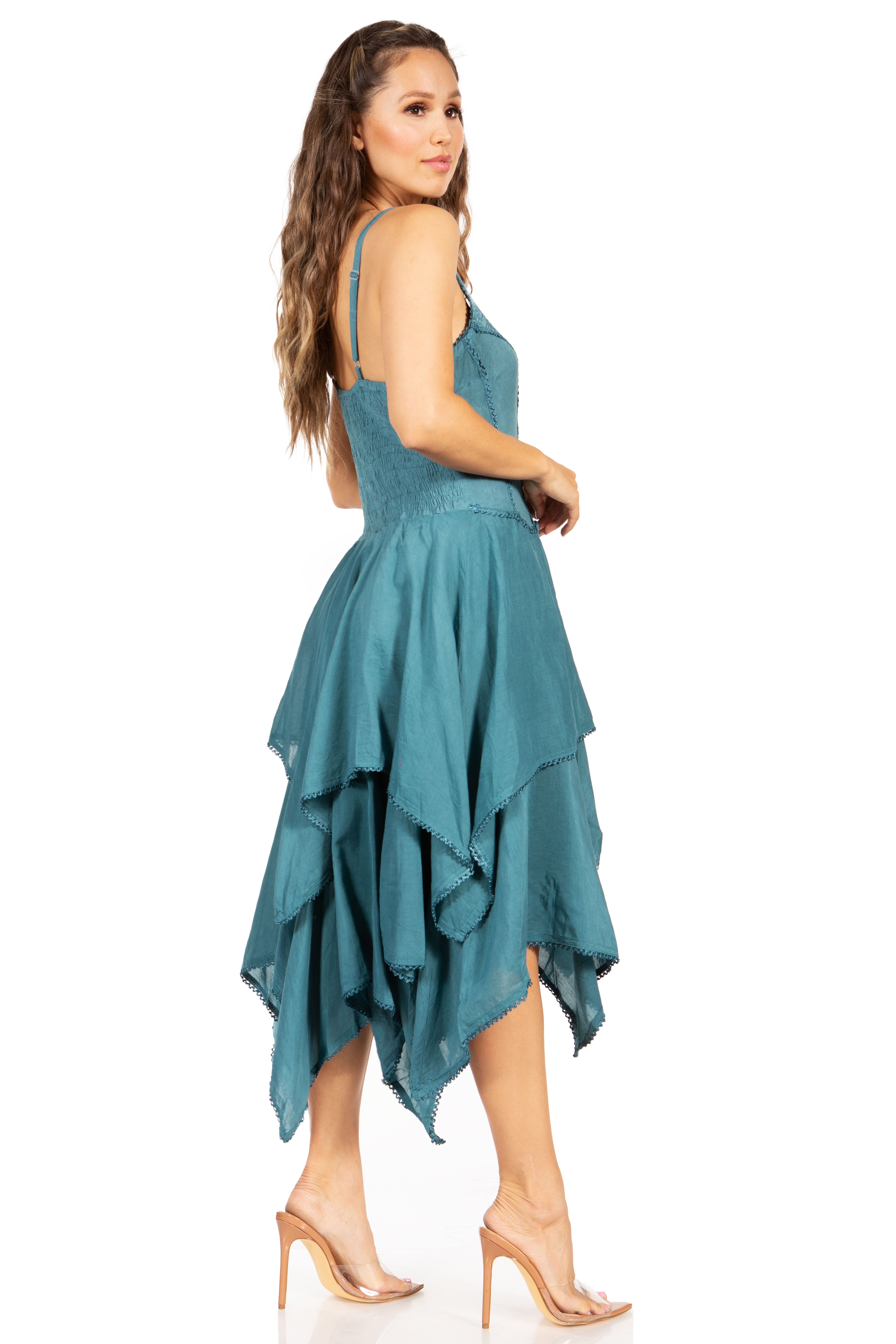 Woman wearing a teal dress with an asymmetrical hem on a white background